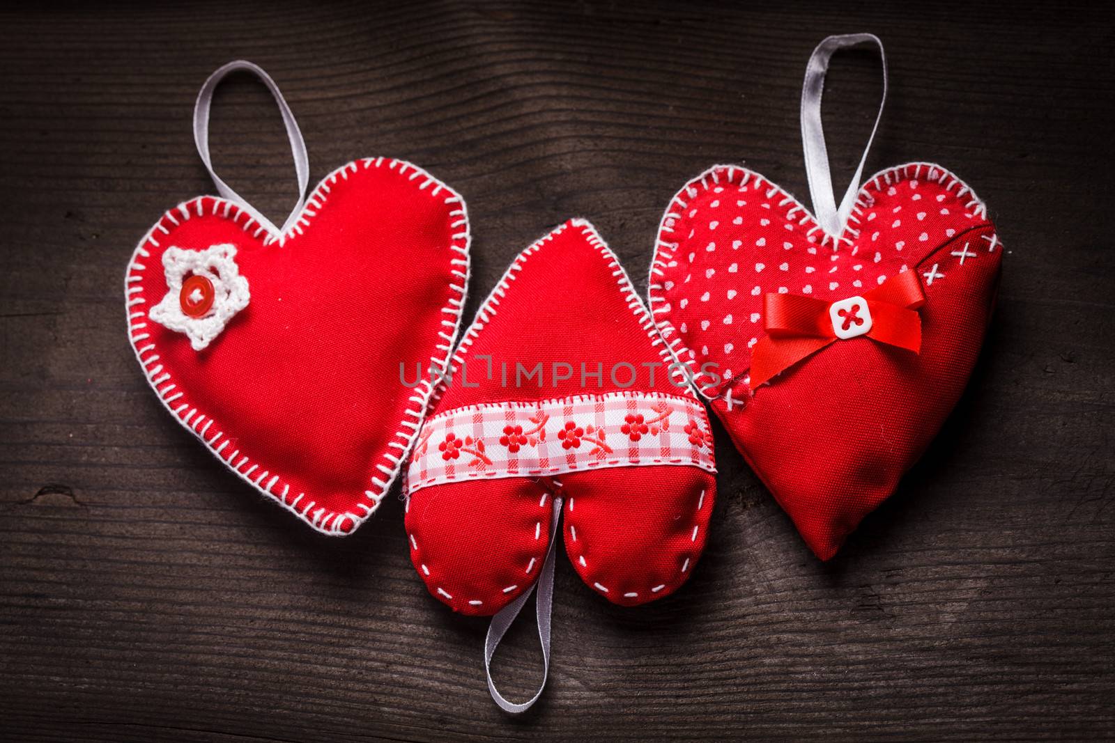 Sewed handmade red hearts on wooden background