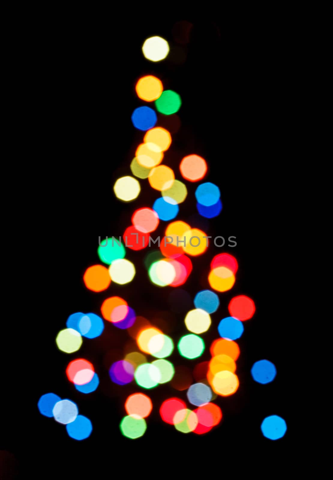 Blurred colorful lights as a silhouette of Christmas tree on black
