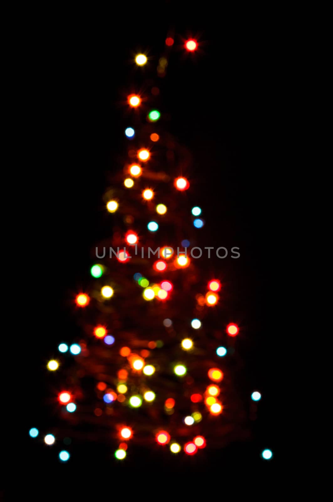 Blurred colorful lights as a silhouette of Christmas tree on black