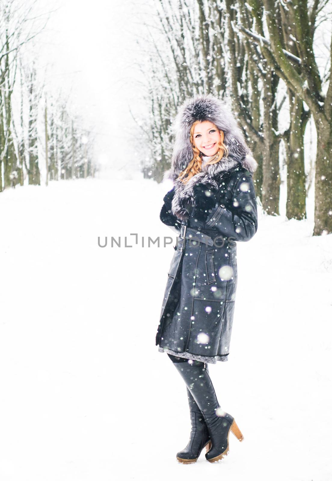 Woman is walking in park alley in winter