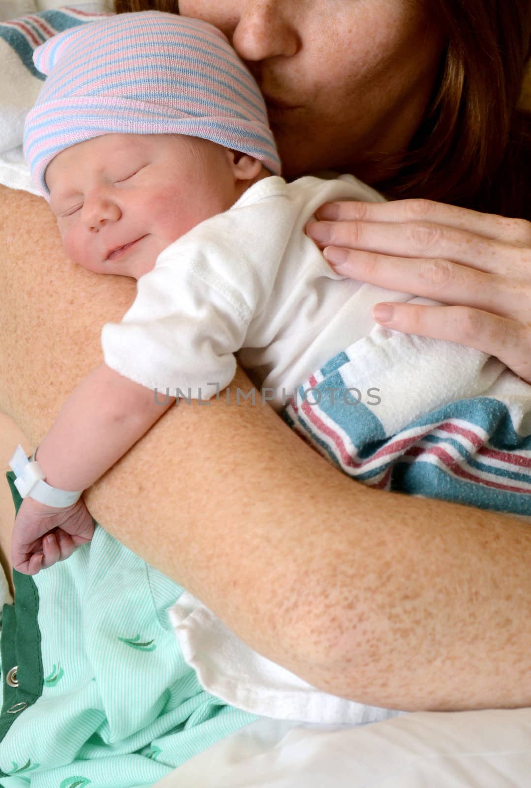 mother kissing and holding smiling newborn baby