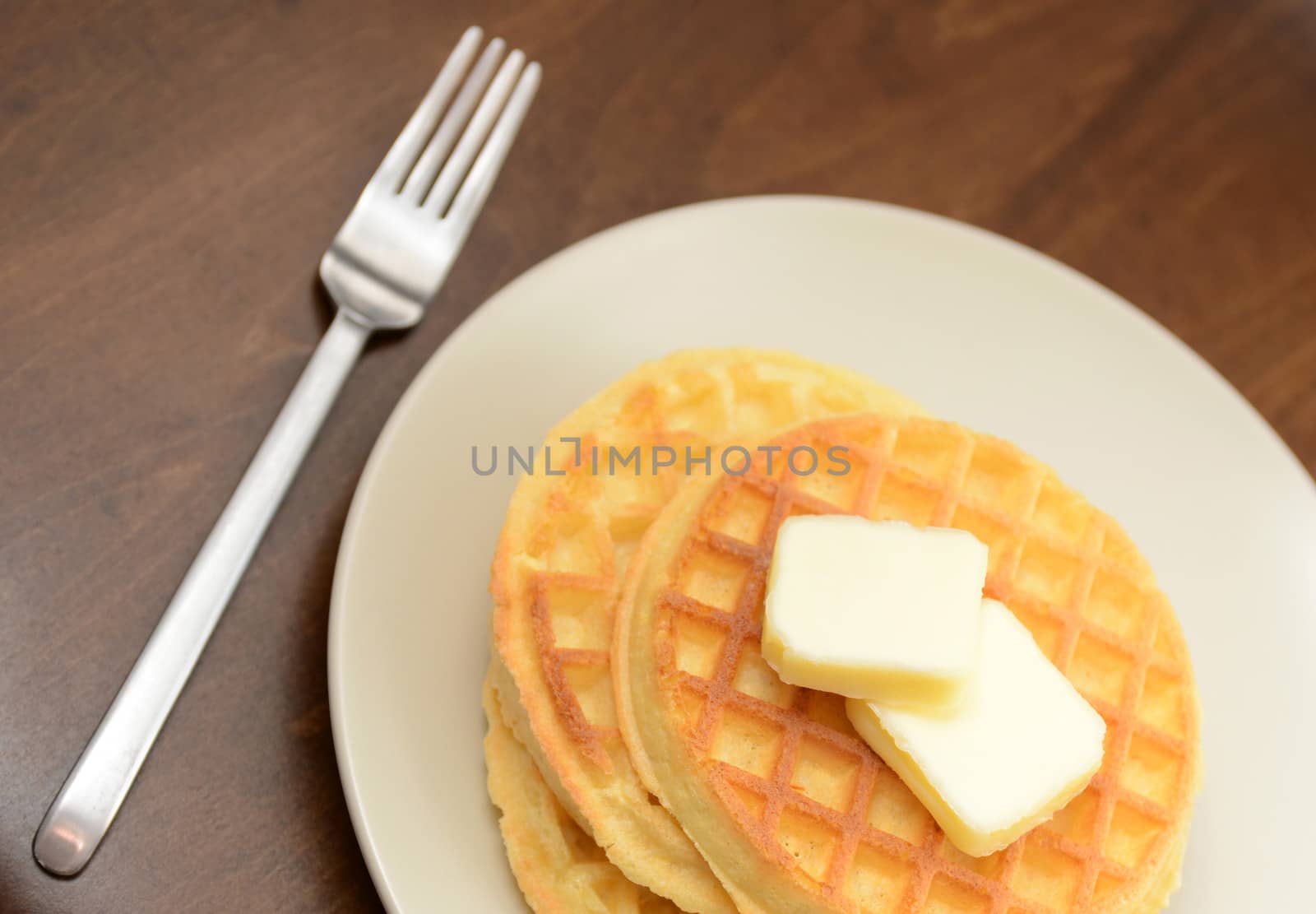 waffles and butter on white plate and rustic background