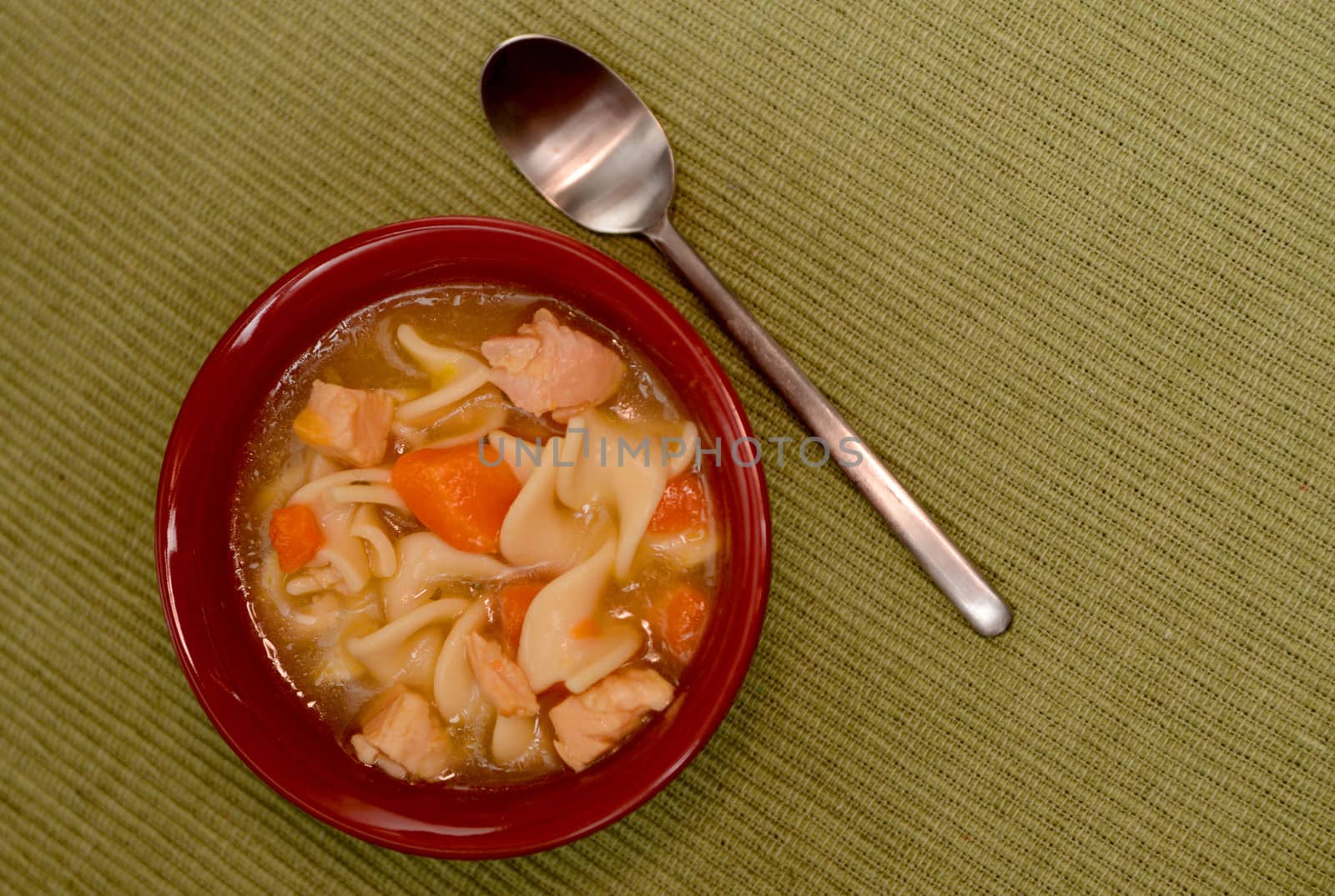 chicken noodle soup in red bowl with spoon