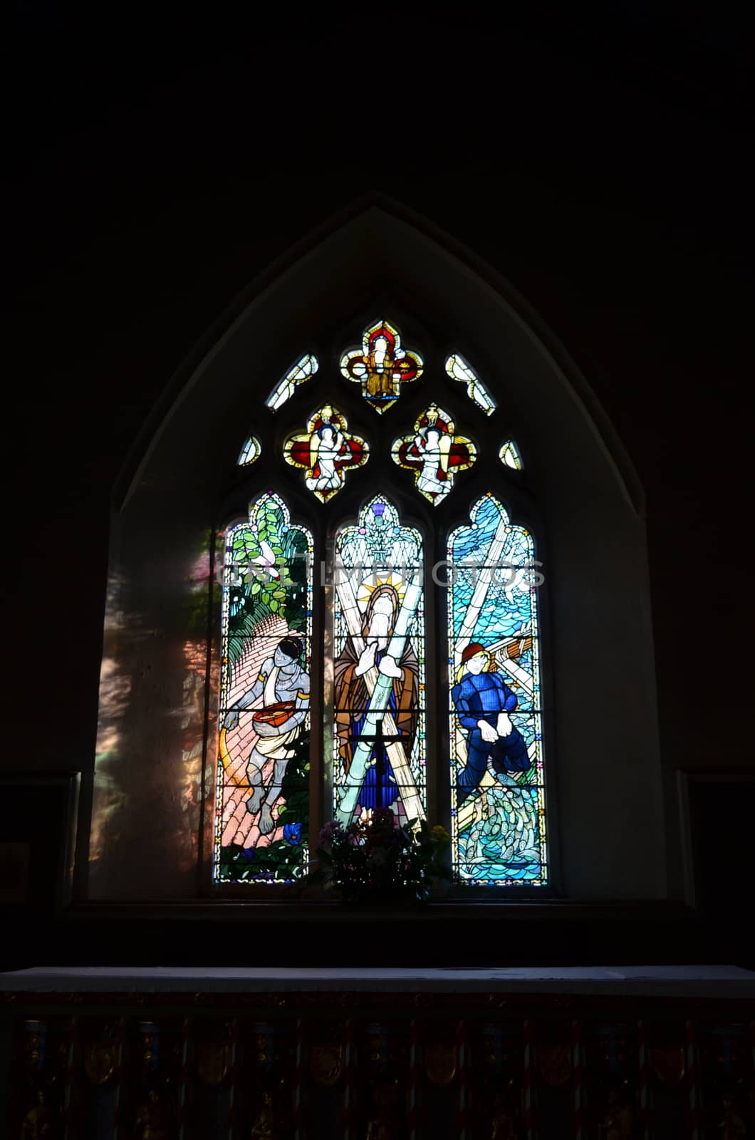 Brightly coloured stained glass window above a church alter In England.