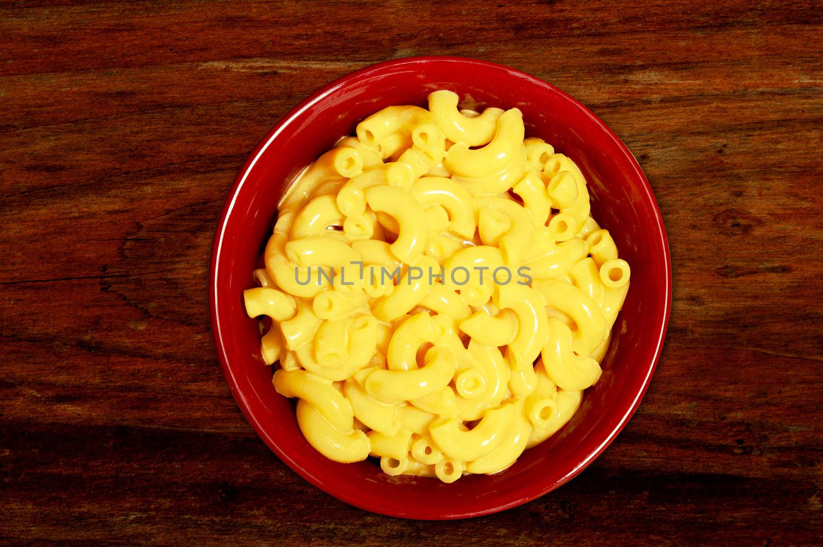 mac and cheese - cheesy pasta in red bowl on wood background