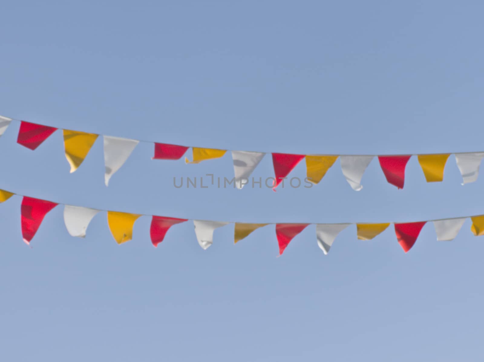 Two rows of colorful triangular flags occur against a background of blue sky