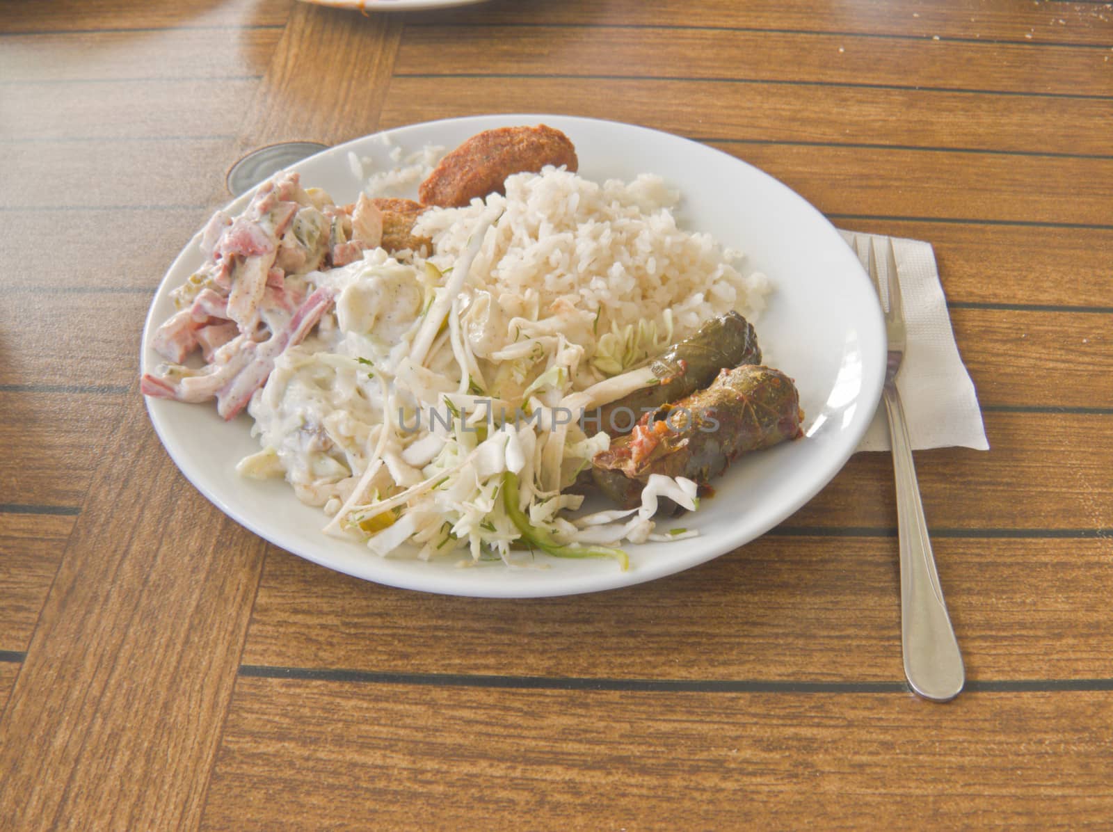 On the table in the ceramic plate dish, consisting of vegetable salads, meat cutlets and rice