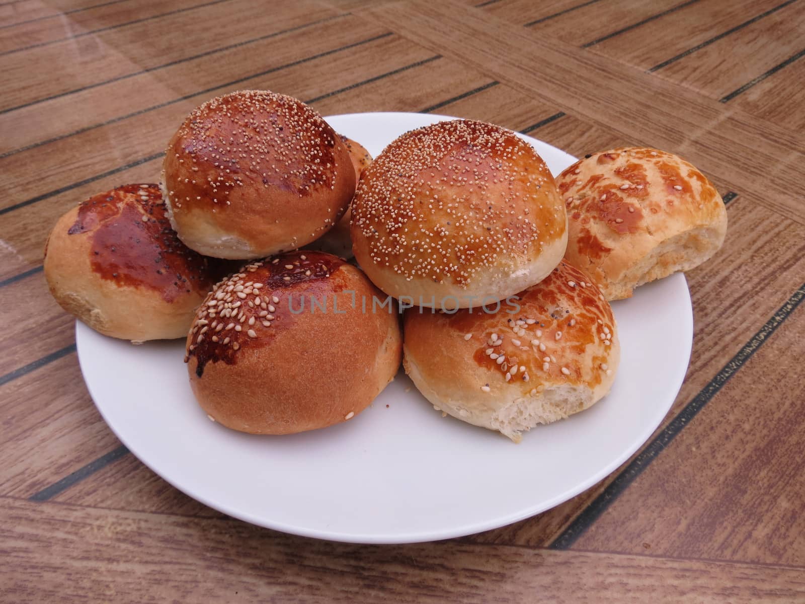 On a white plate neatly laid out round buns with sesame and poppy seeds                          