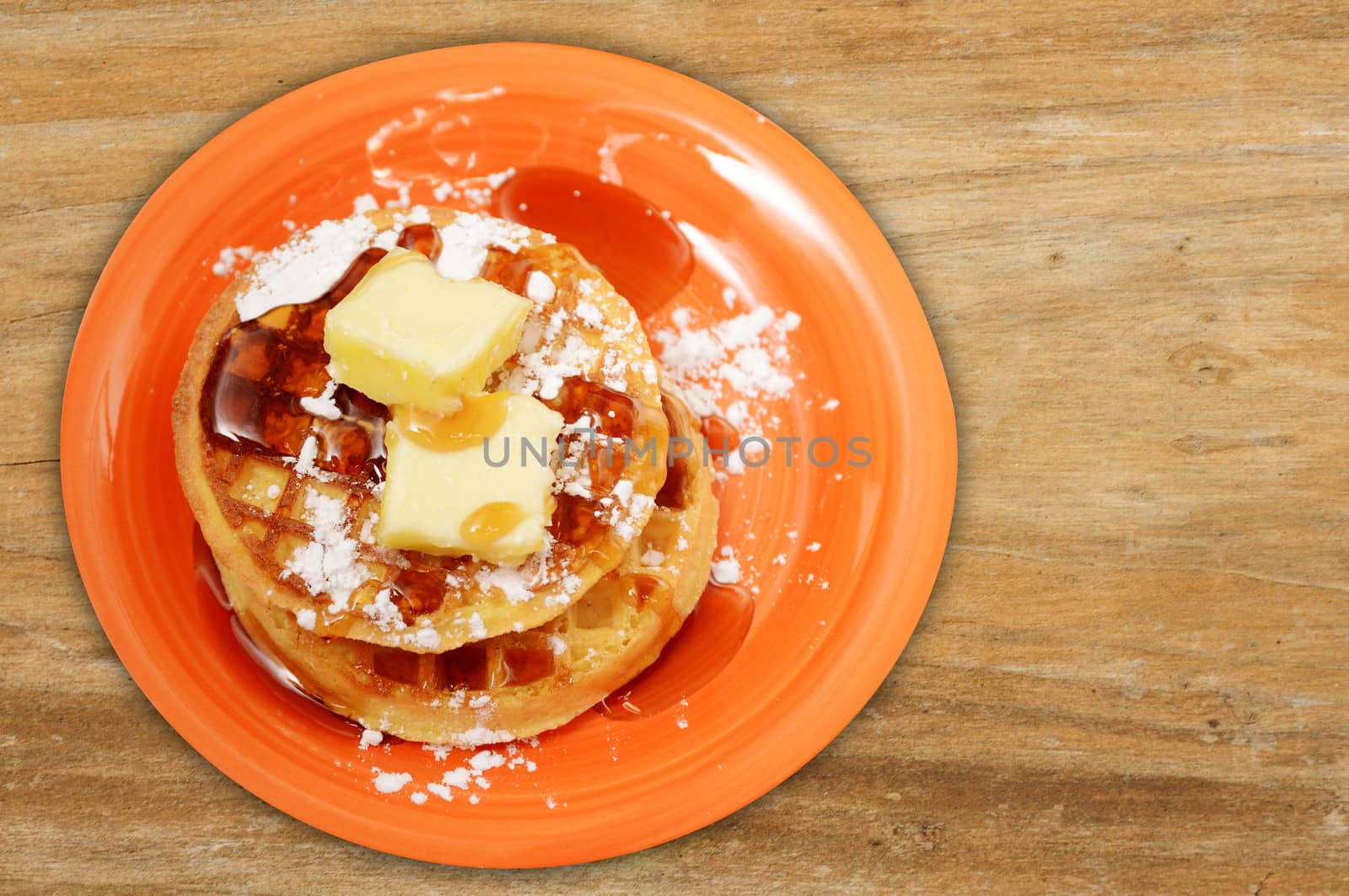 waffles with butter and syrup on wood background