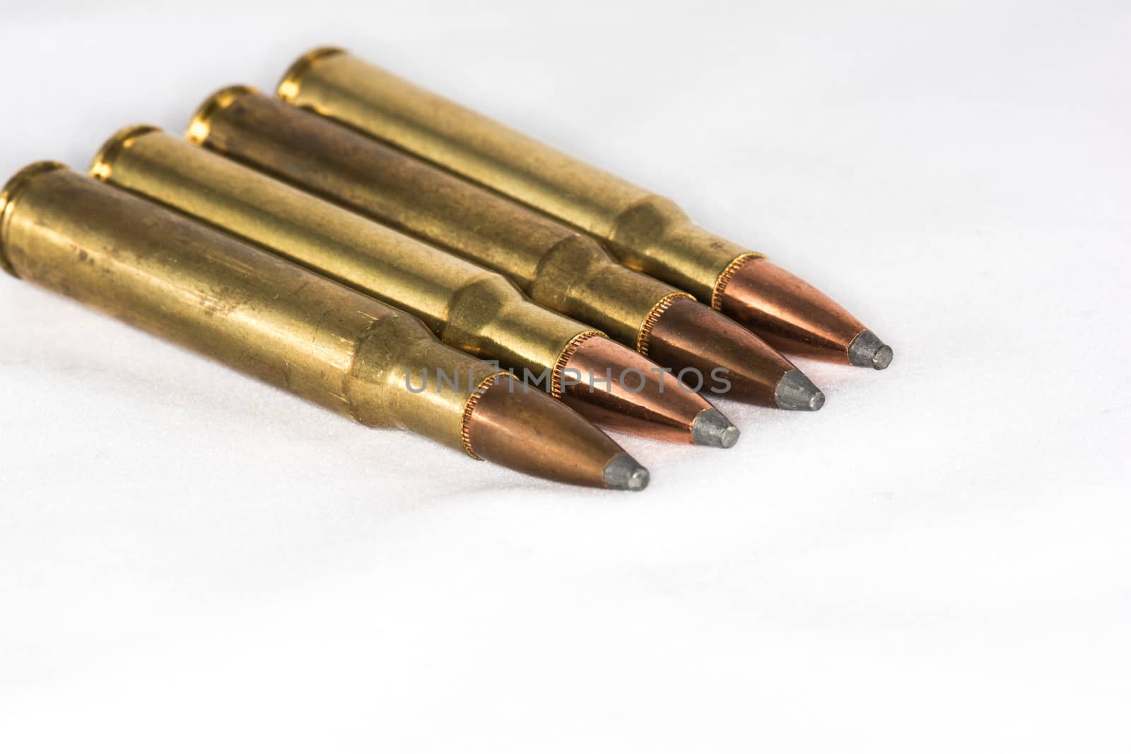 A few rifle bullets lined up in a row on white background