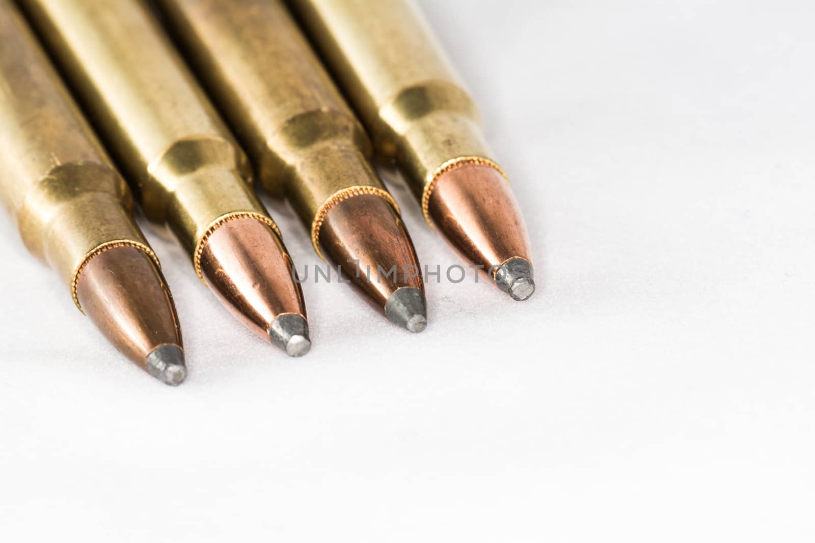 Tips of a few rifle bullets lined up in a row on white background