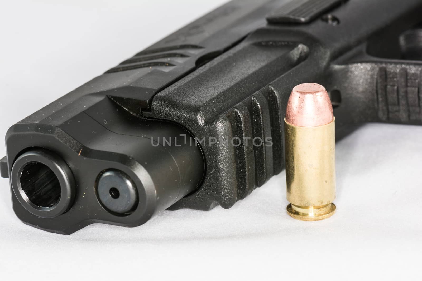 Tip of black hand gun and a bullet on white background