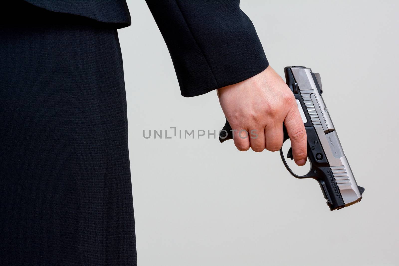 Close up of a the back side of a woman in business suit holding a hand gun