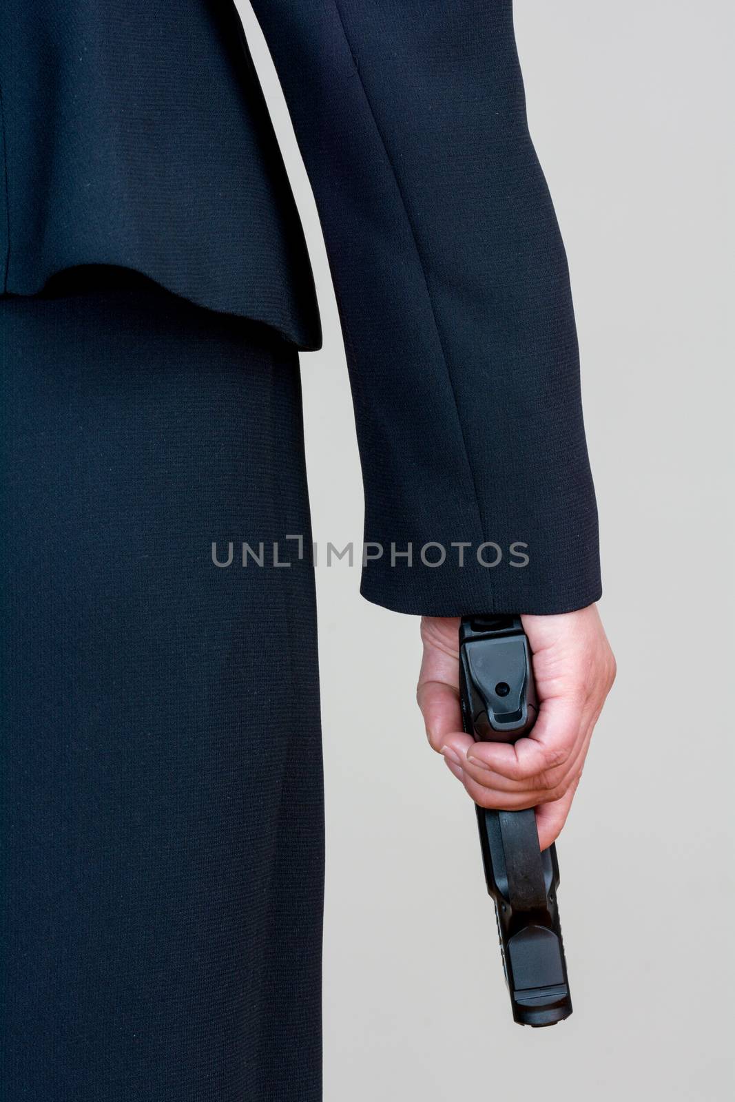 Close up of a the back side of a woman in business suit holding a hand gun
