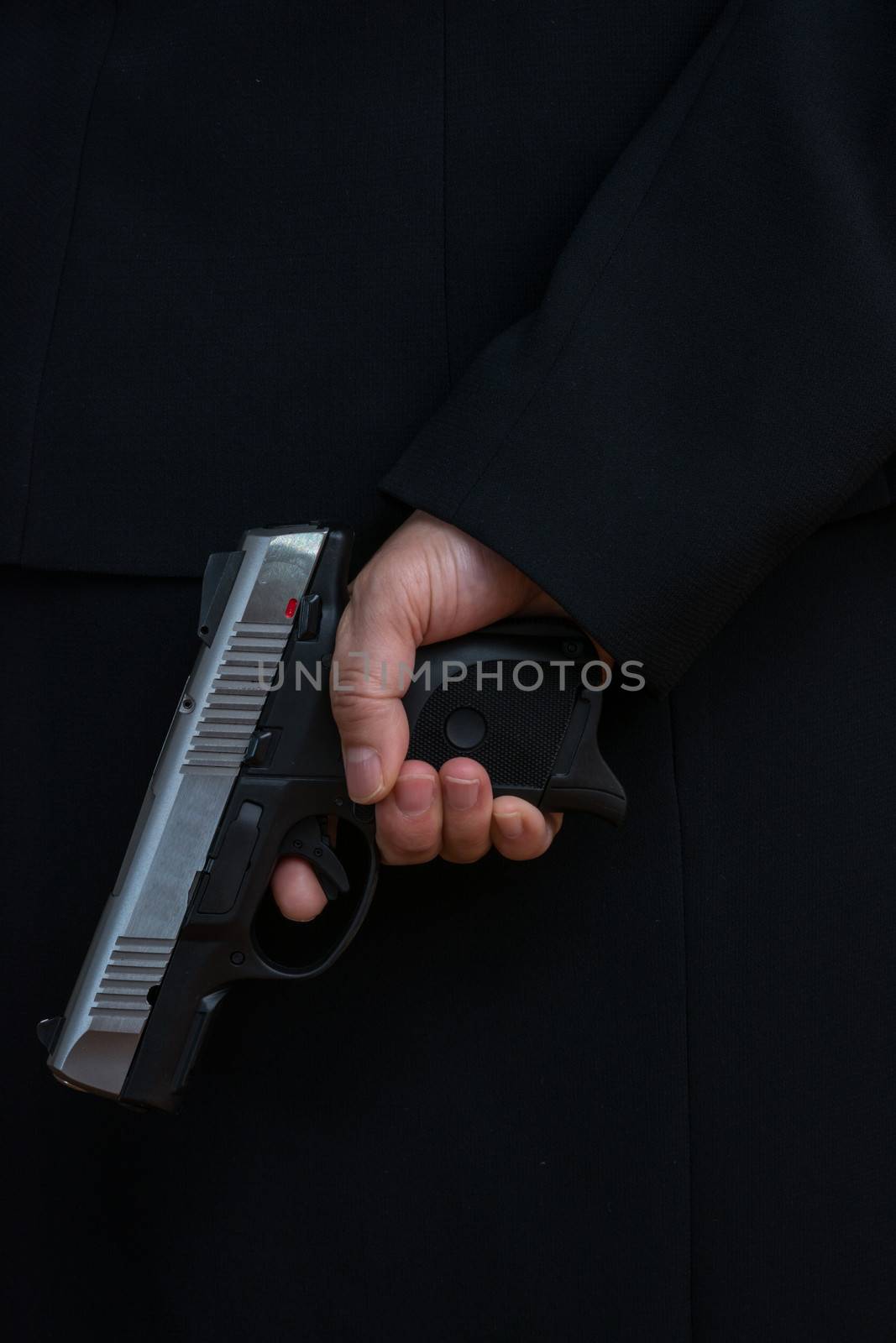 Close up with woman in business suit hold a pistol to dark suit 