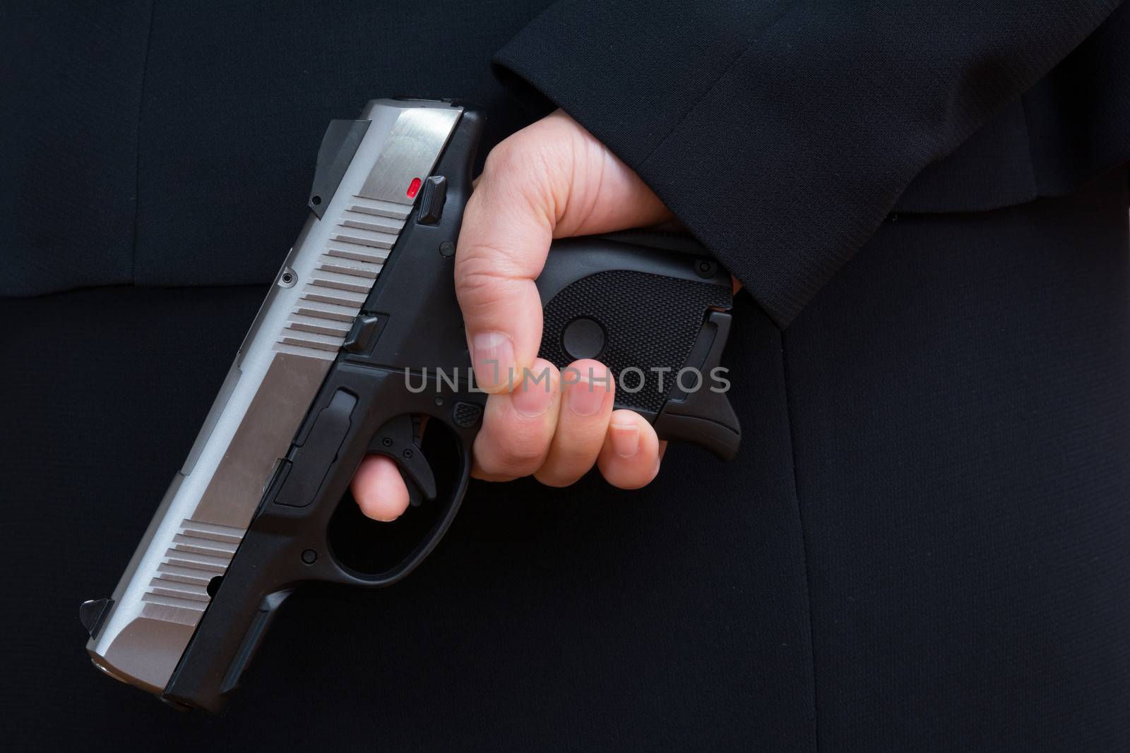 Close up with woman in business suit hold a pistol to dark suit 