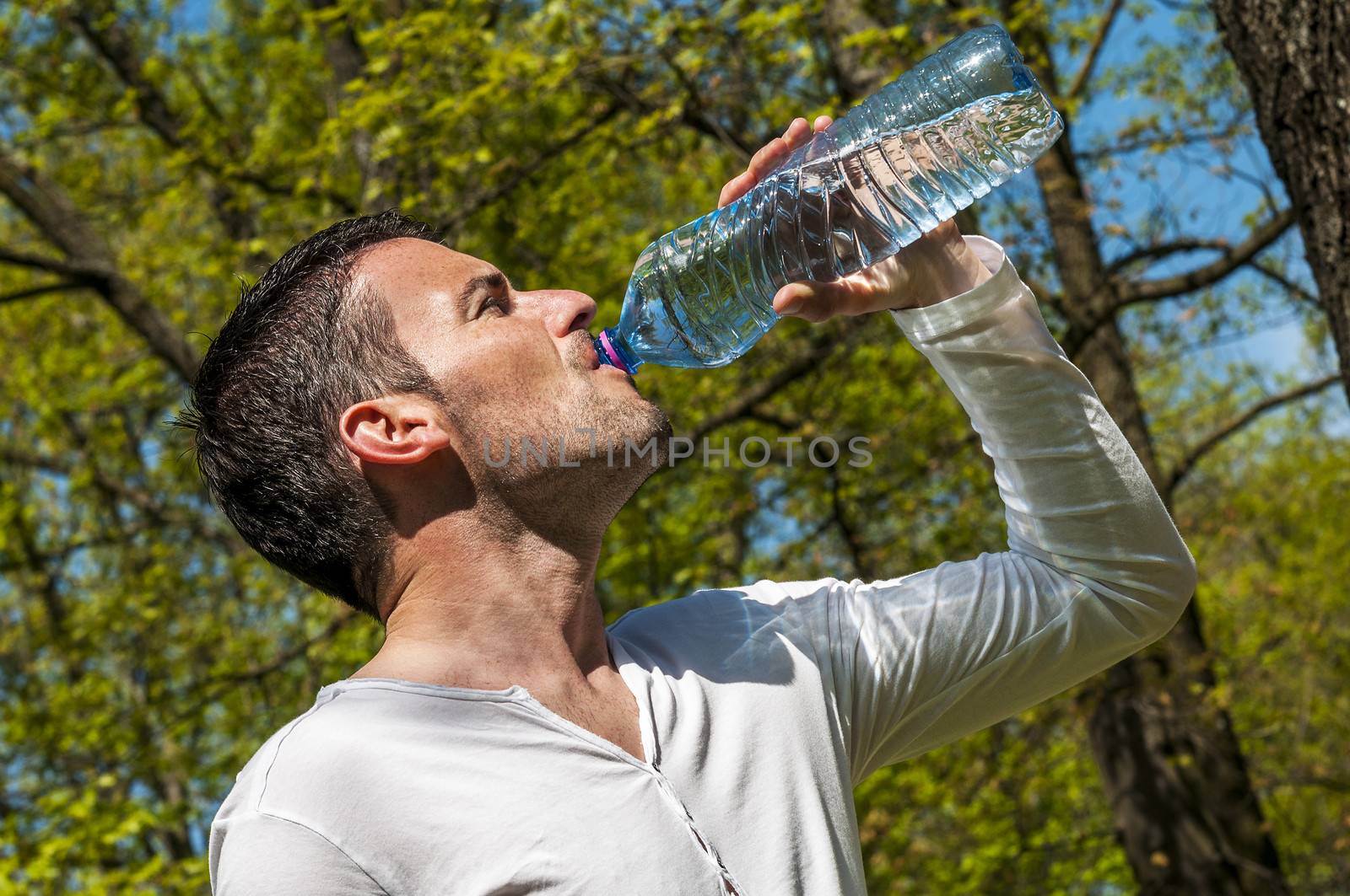 Man is drinking water against a natural background