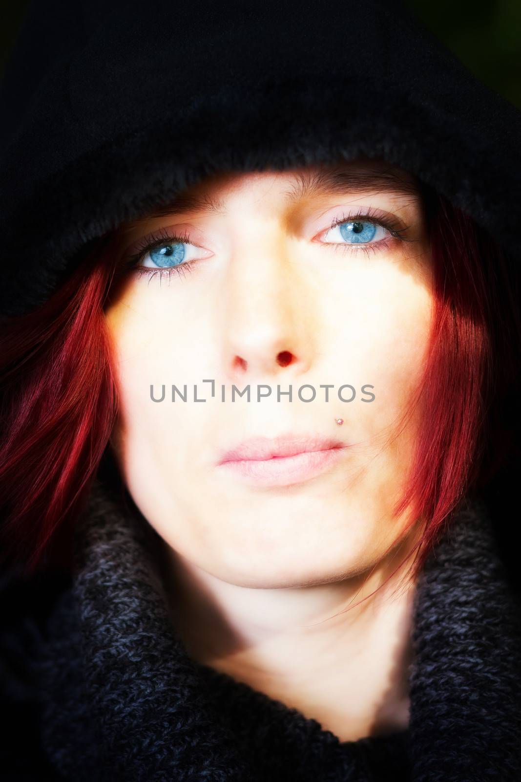Close up head portrait of a beautiful redhead woman with startling blue eyes and a serene expression
