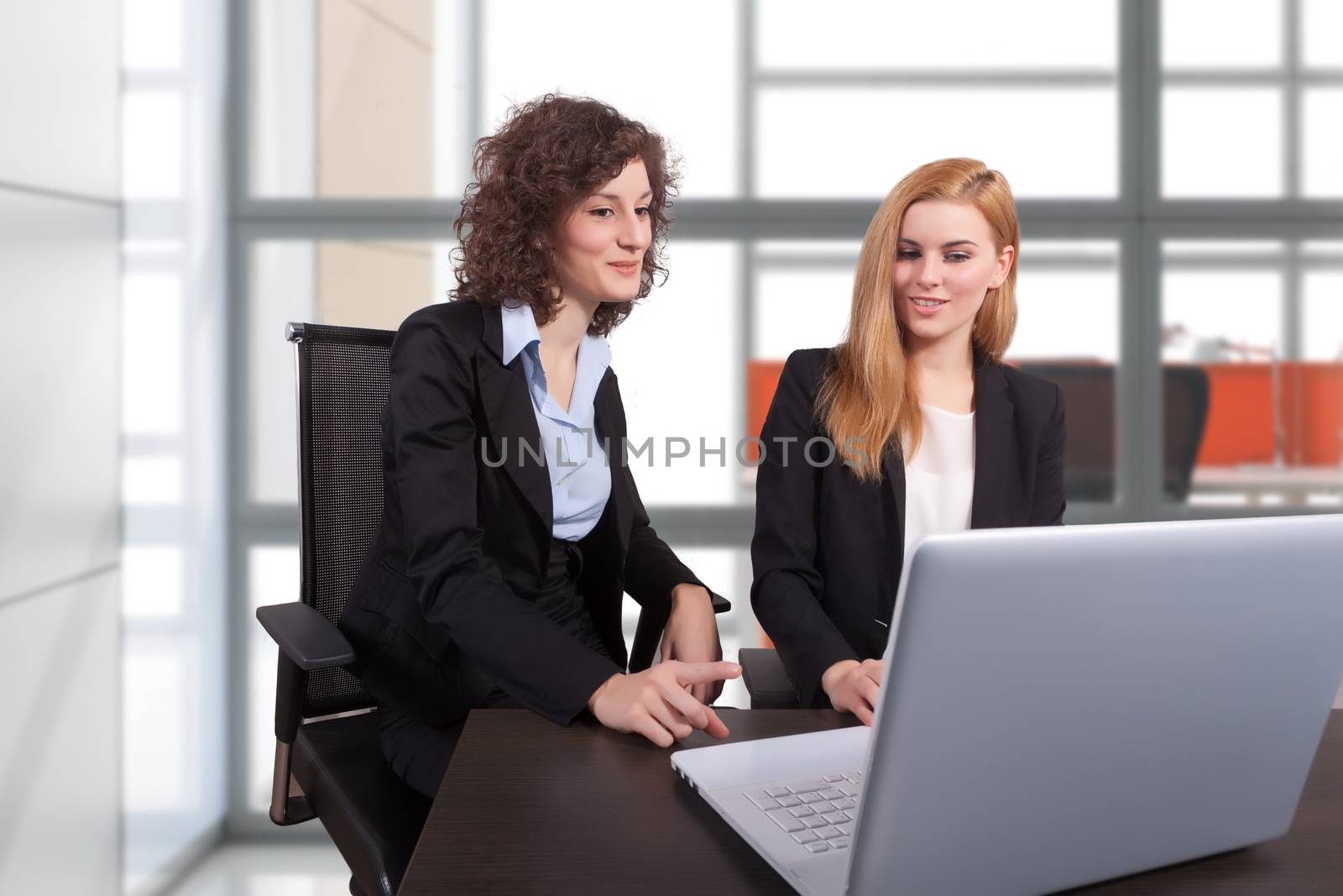 two businesswoman working in office at laptop