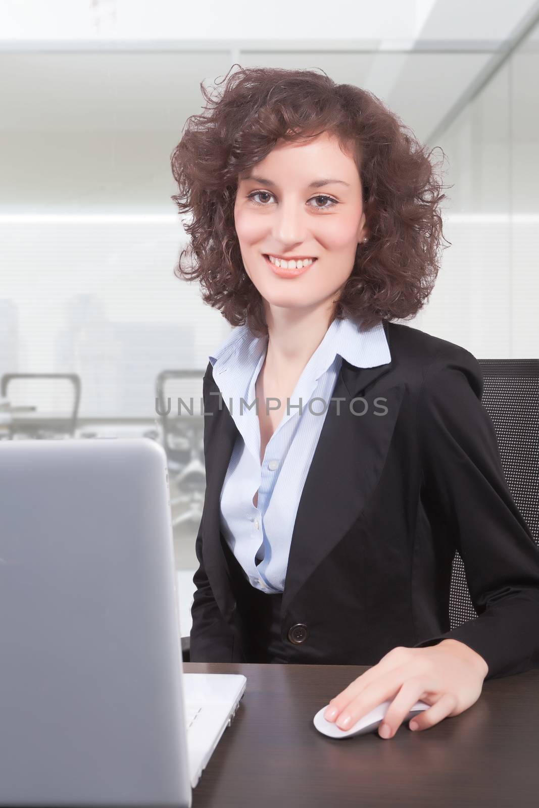 A woman sits at a desk in front of a computer screen.