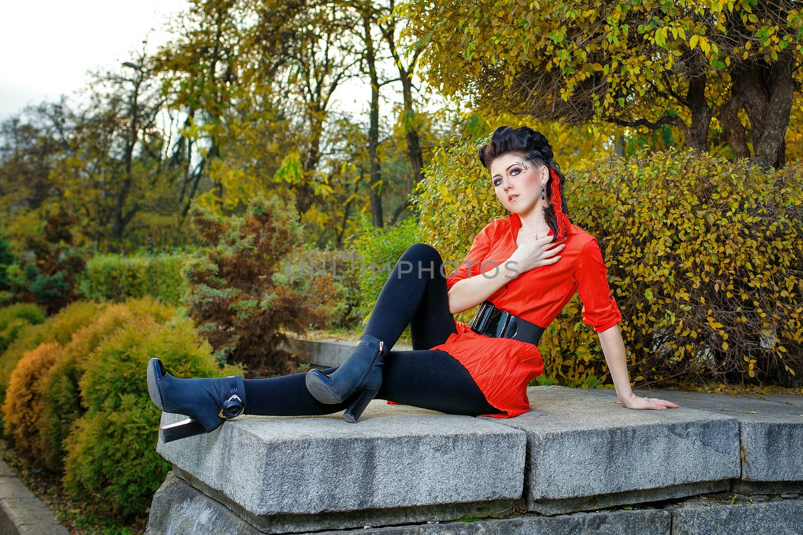Attractive young girl in a red shirt walks in the city park