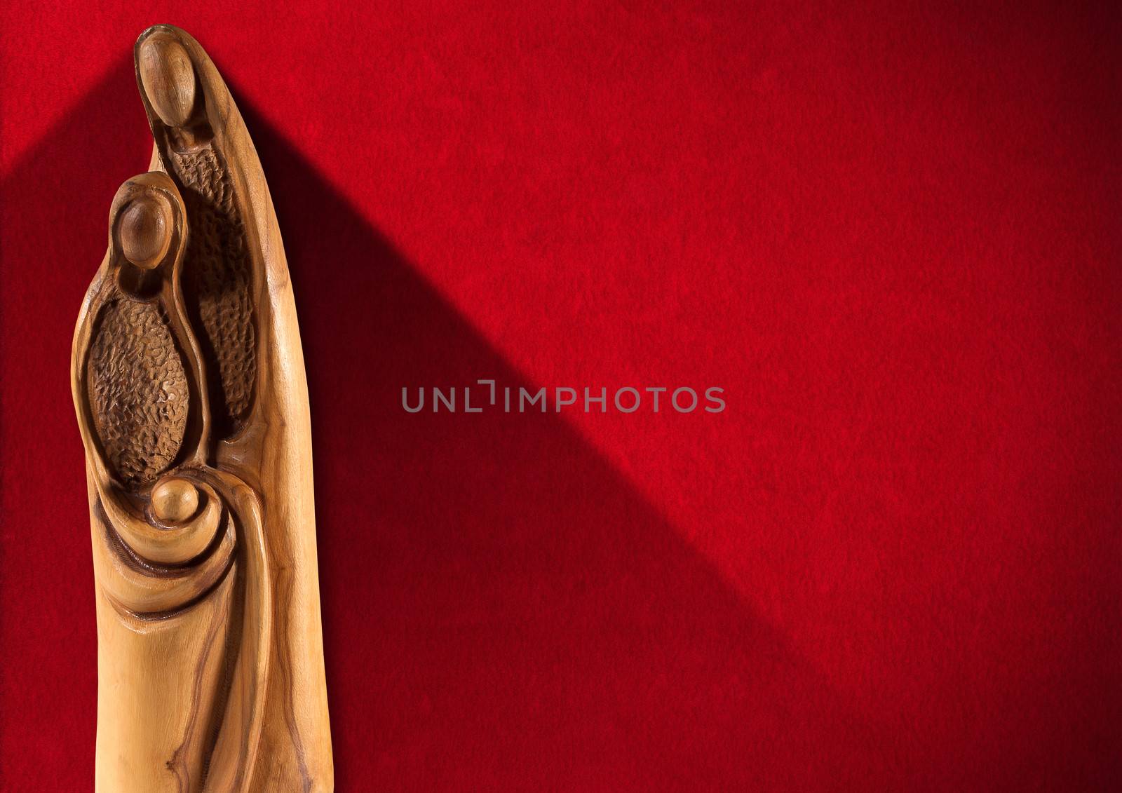 Wooden Christmas Crib with Mary, Joseph and baby Jesus on red velvet background with shadows