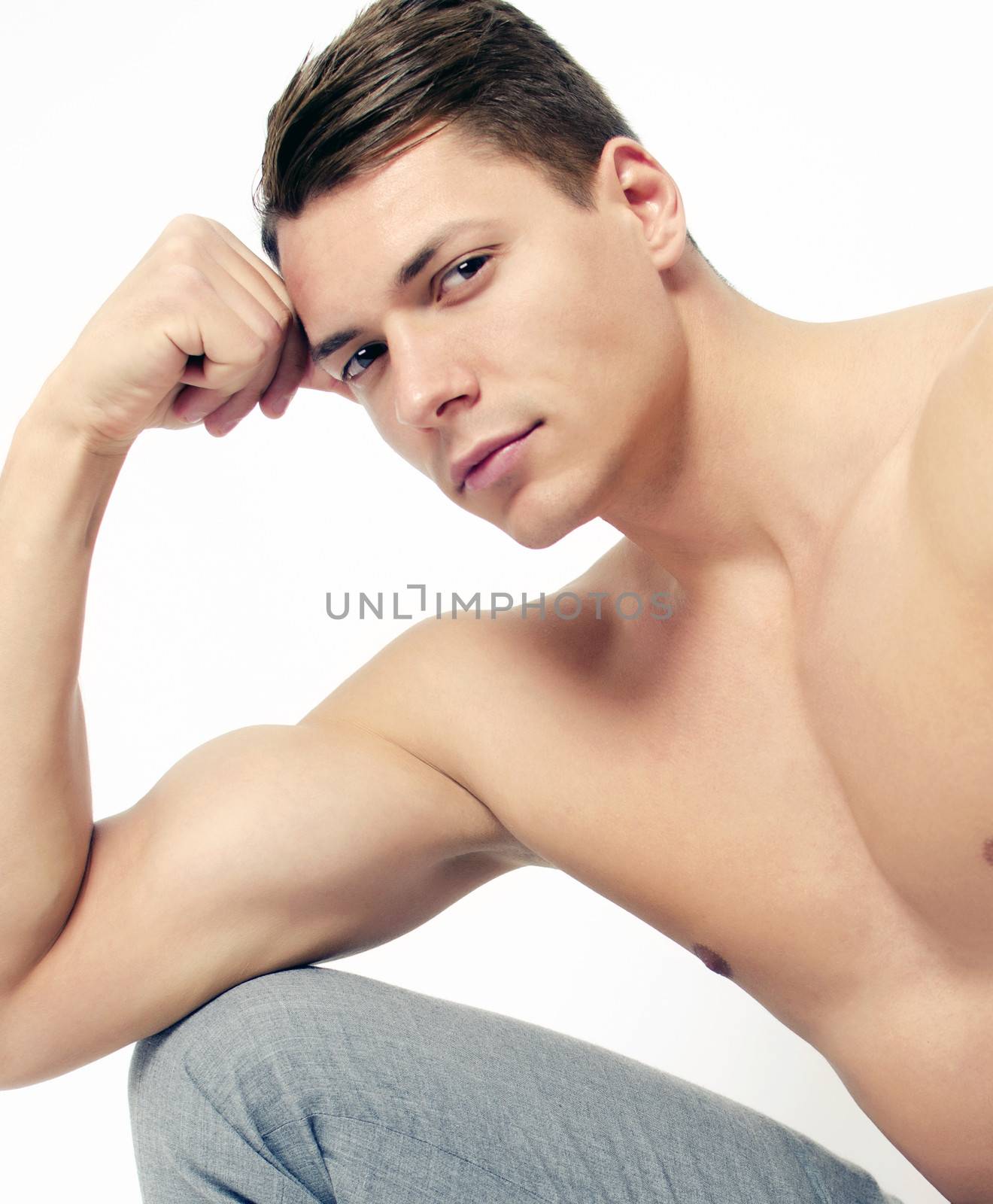 Close up of a muscular man posing on white background looking at camera