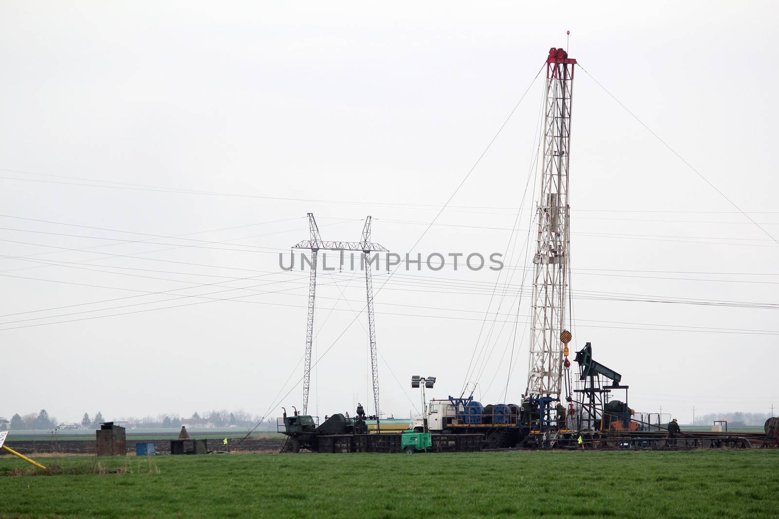 oilfield with workers and land oil drilling rig by goce