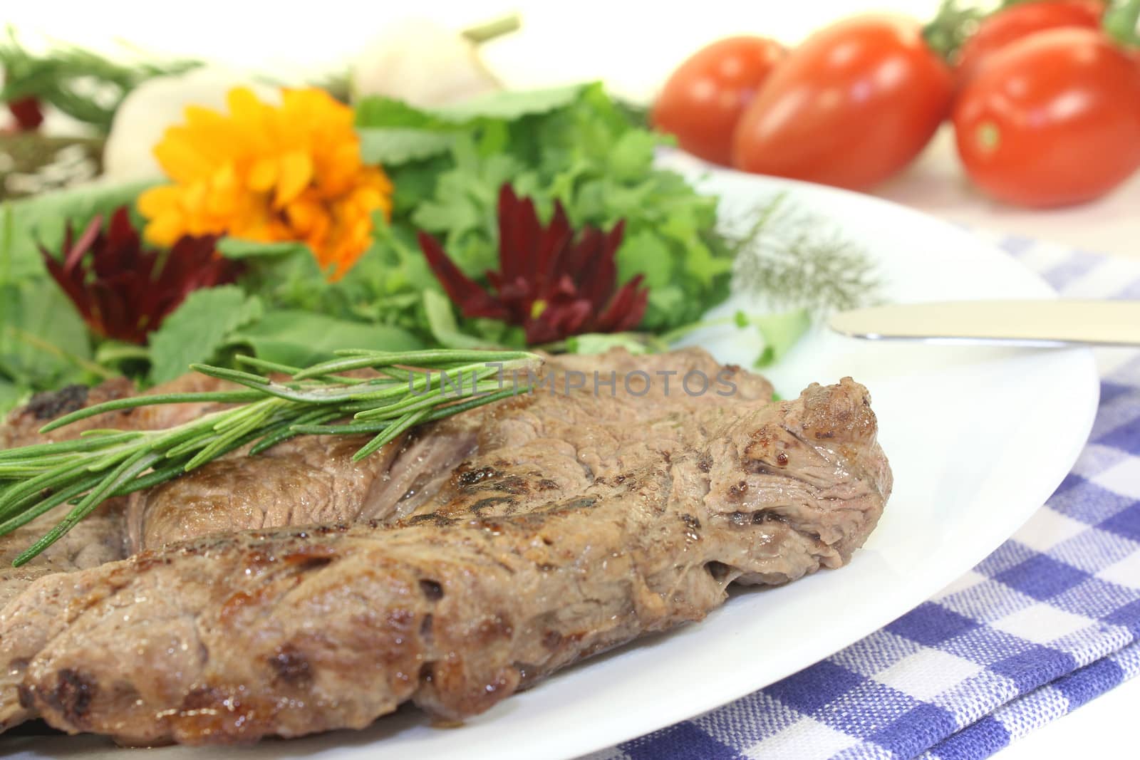 fried Sirloin steak with wild herb salad on a light background