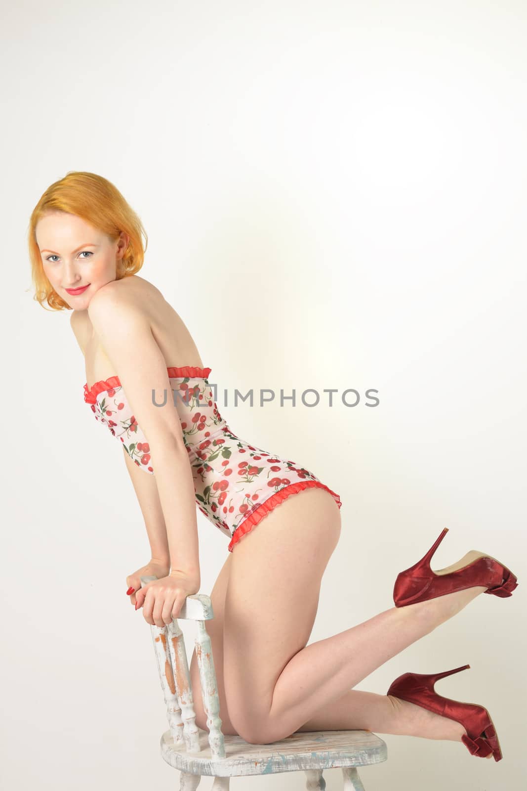 Attractive red head kneeling on chair