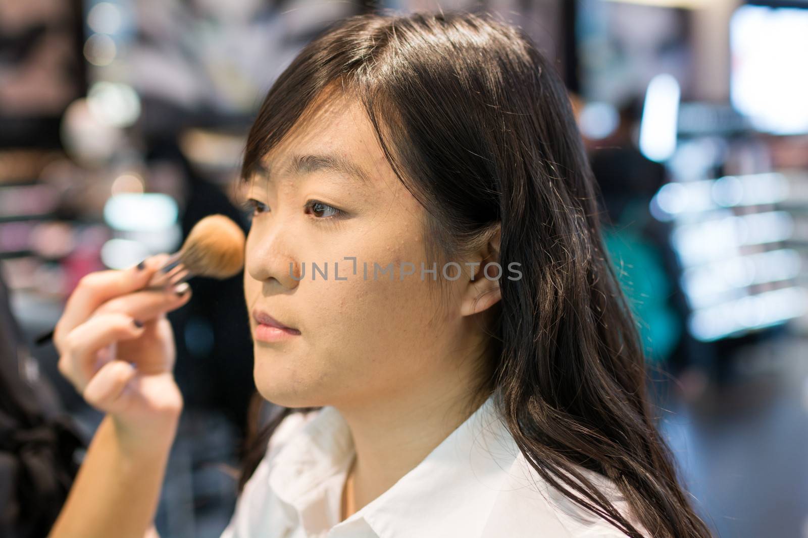 Young Asian woman applying facial powder with a brush