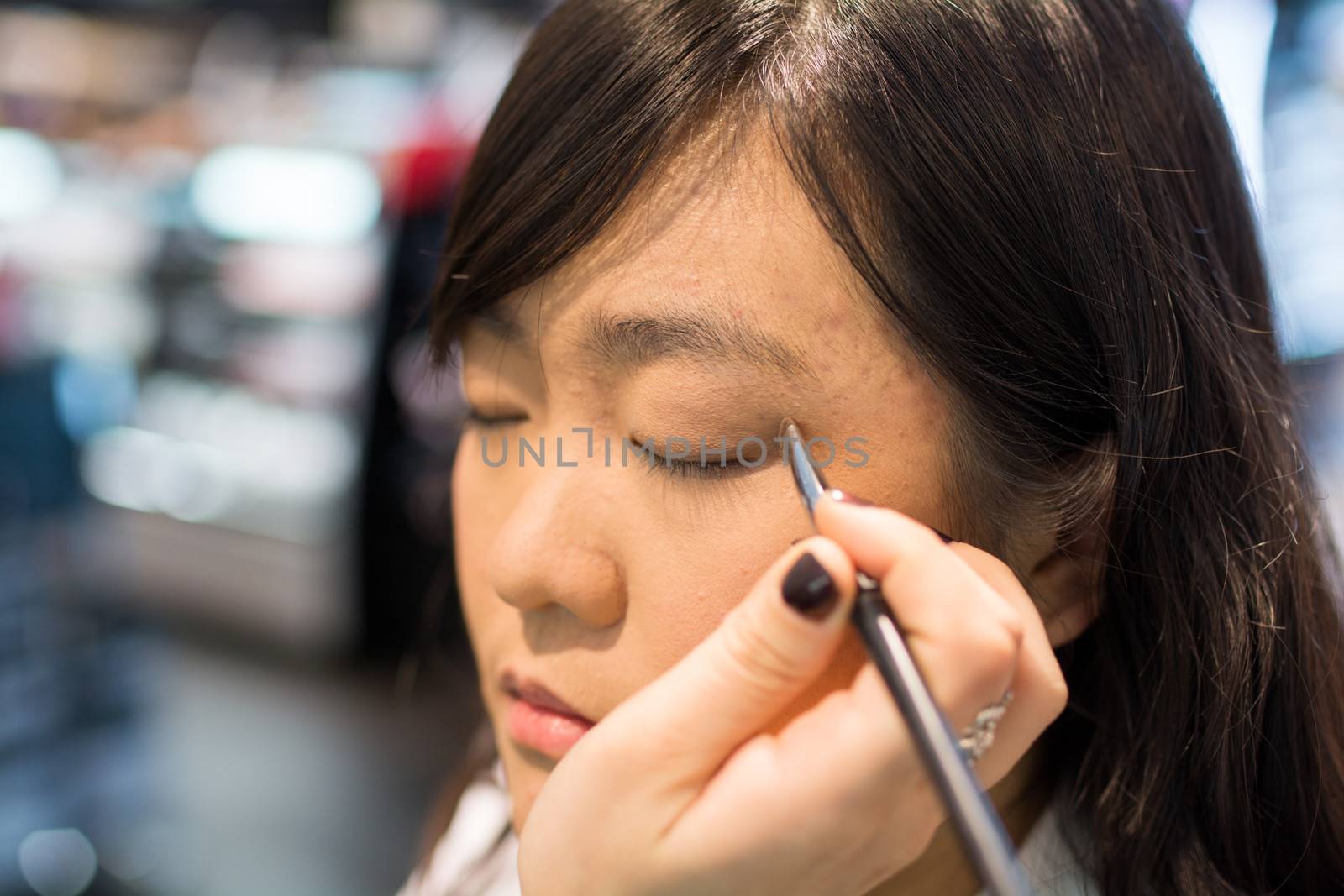 Young Asian woman applying eye liner with a small brush