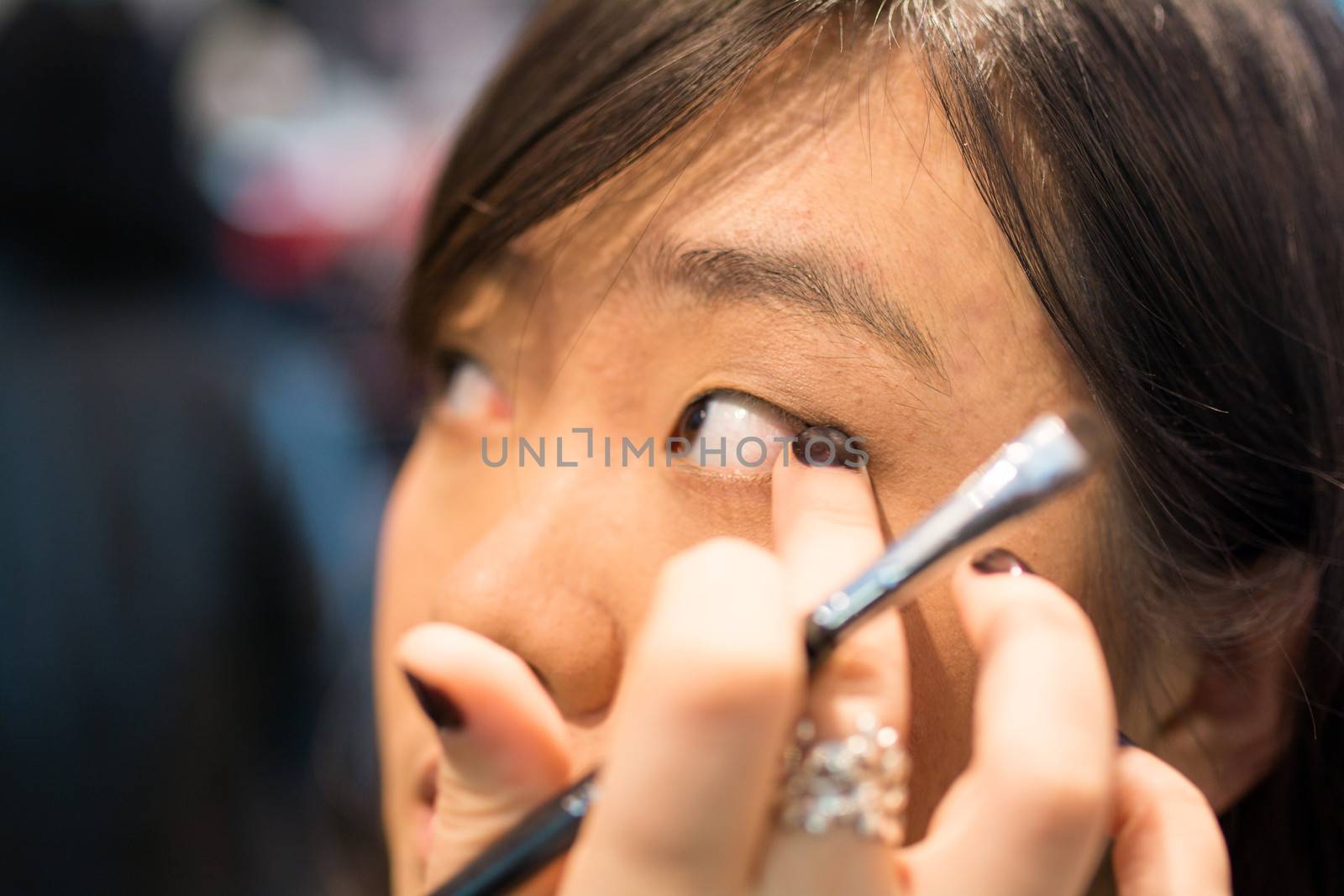 Young Asian woman applying eye liner with a small brush