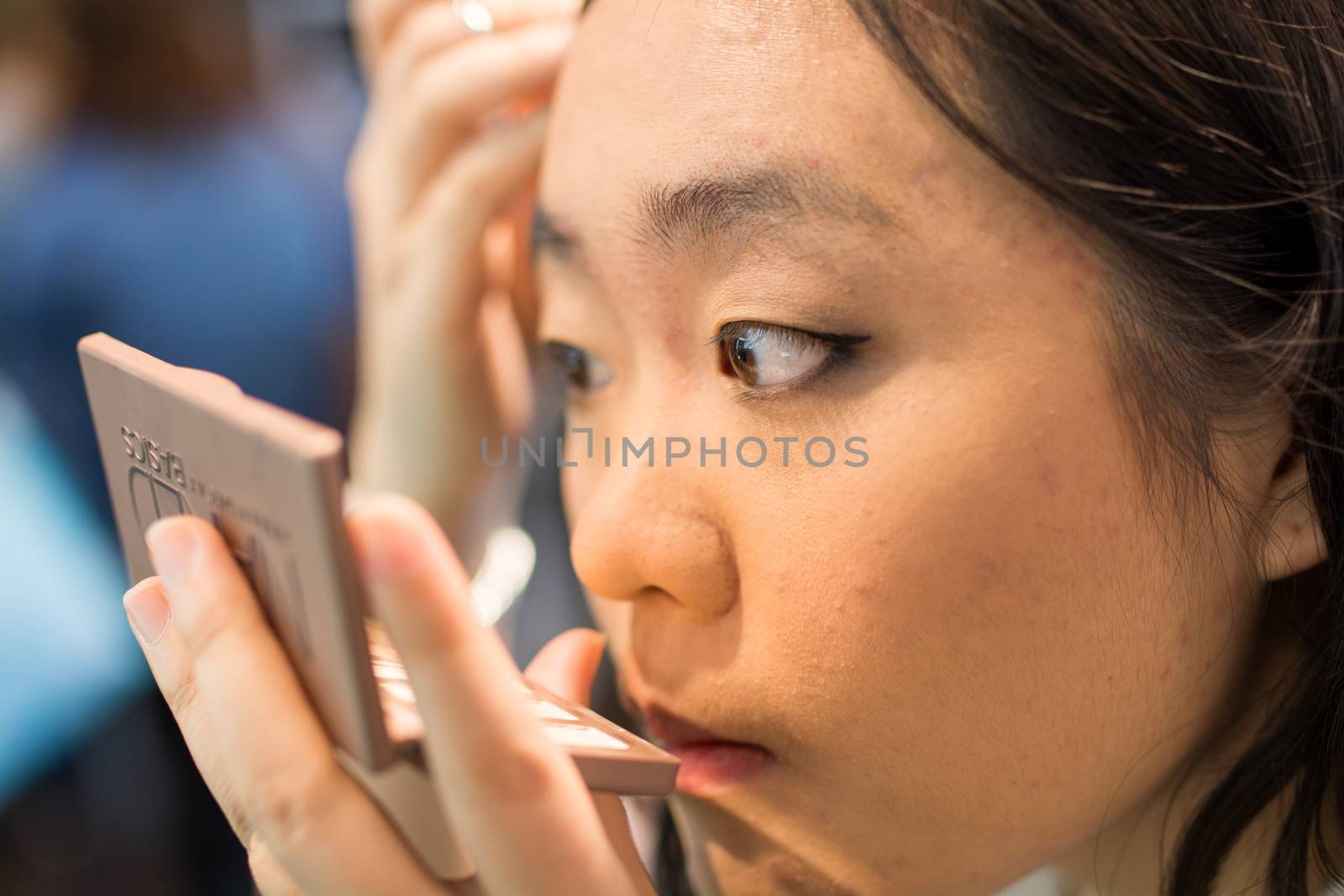 Woman applying cosmetics by IVYPHOTOS