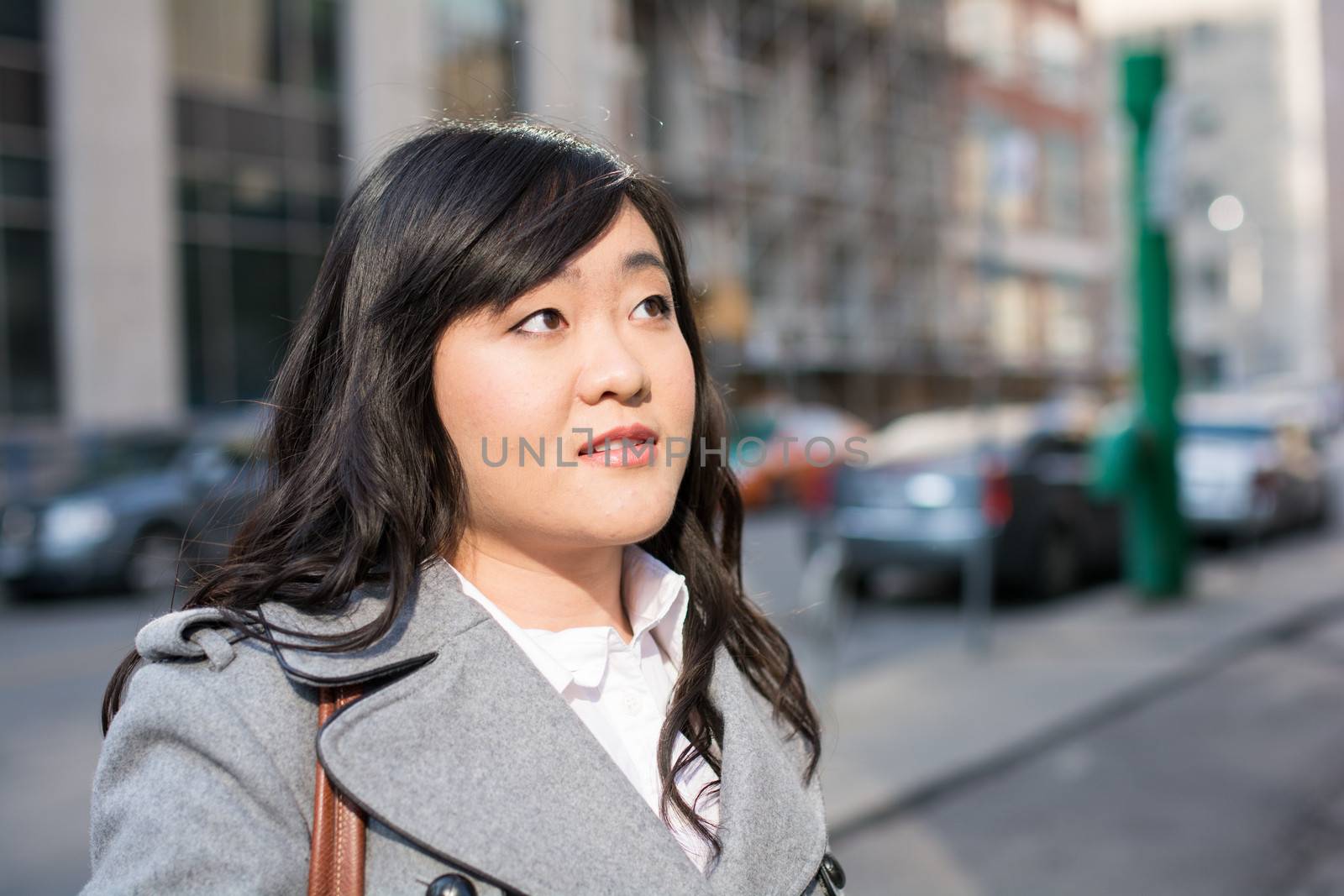 Young Asian woman in coat on a street in a large city