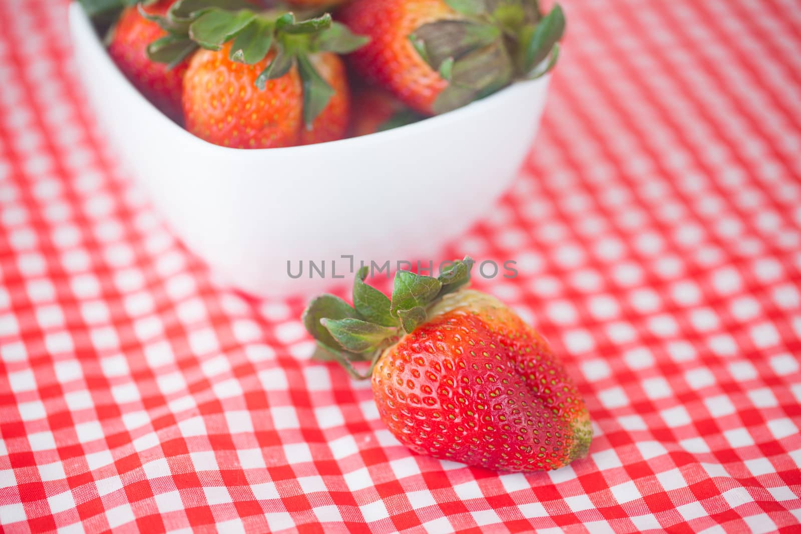 strawberries in bowl on checkered fabric by jannyjus
