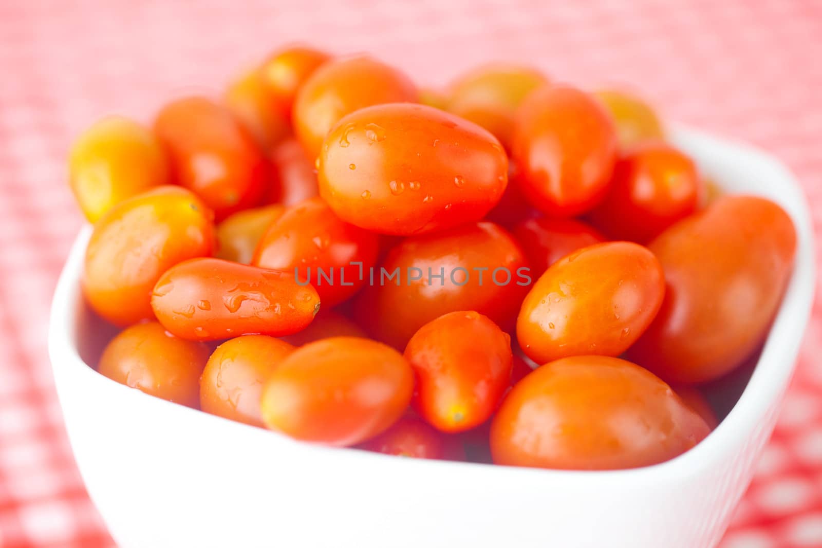 cherry tomatos in bowl on checkered fabric by jannyjus