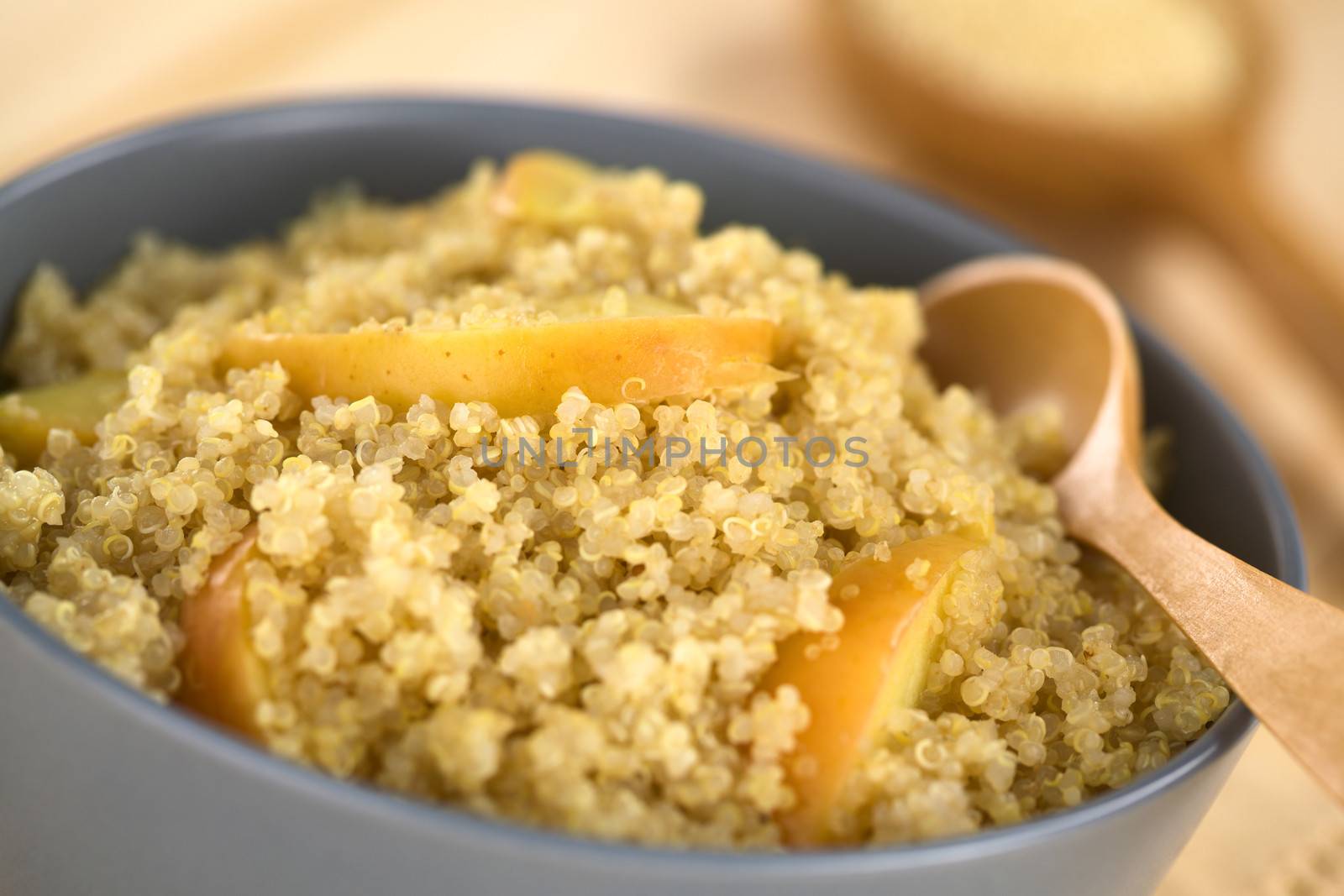 Quinoa porridge with apple and cinnamon, which is a traditional Peruvian breakfast, served in a bowl (Selective Focus, Focus on the apple slice in the middle of the porridge)