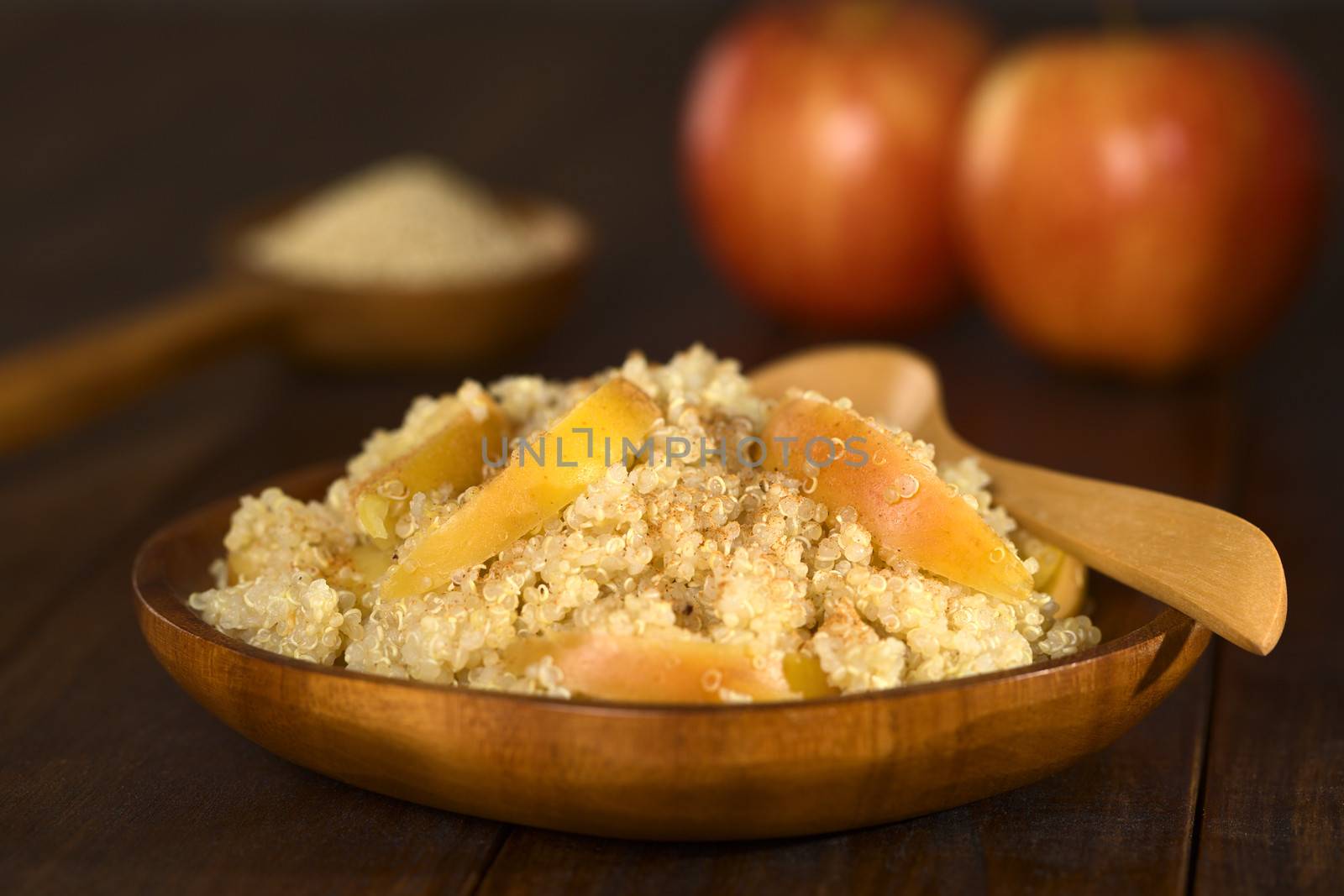 Quinoa porridge with apple and cinnamon, which is a traditional Peruvian breakfast, served on wooden plate (Selective Focus, Focus one third into the porridge)