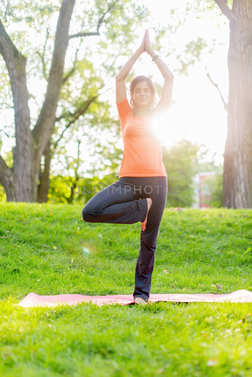 Portrait of a girl meditation and taking yoga poses at sunset under trees