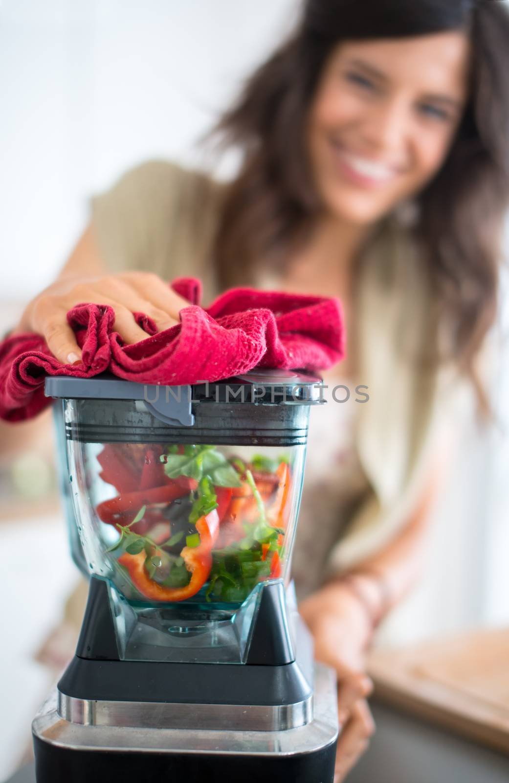 Portrait of a girl using the blender to prepare raw tomato sauce