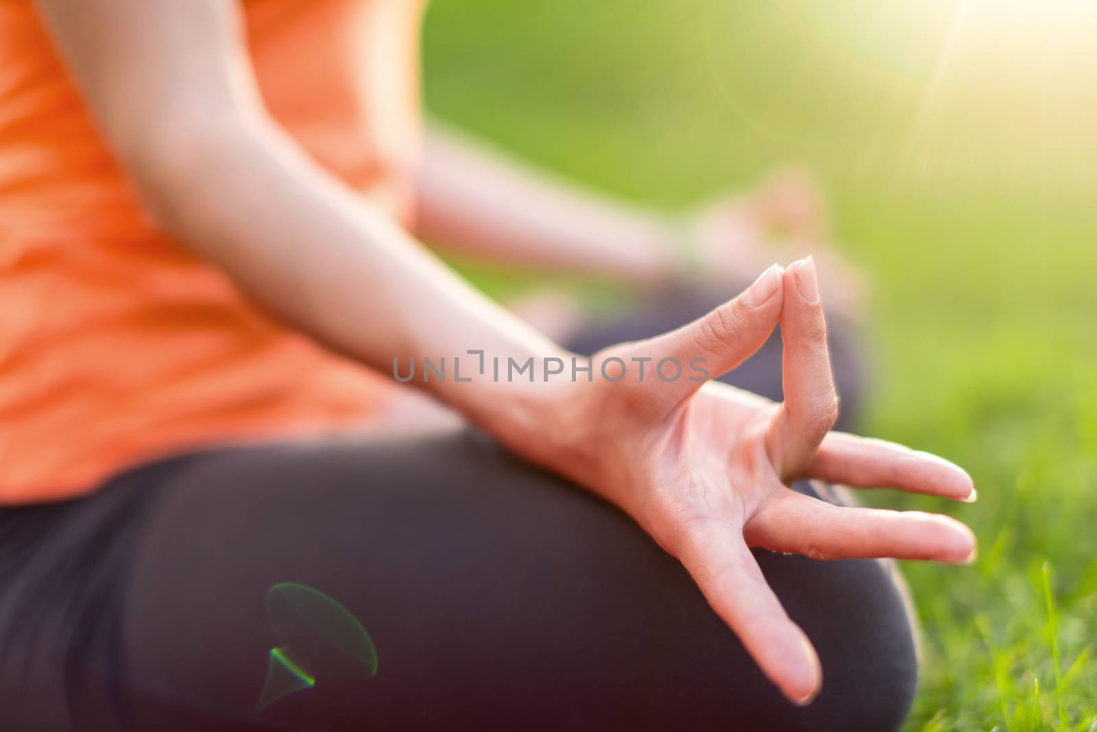 Hand detail of a girl meditation and taking yoga poses at sunset under trees