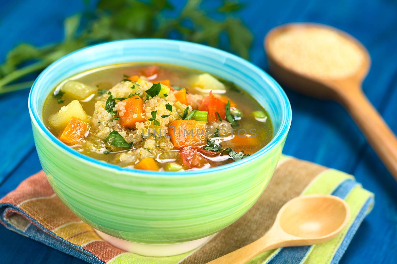 Vegetarian quinoa soup with carrot, potato, leek and tomato, sprinkled with parsley and scallion in colorful bowl (Selective Focus, Focus one third into the soup)