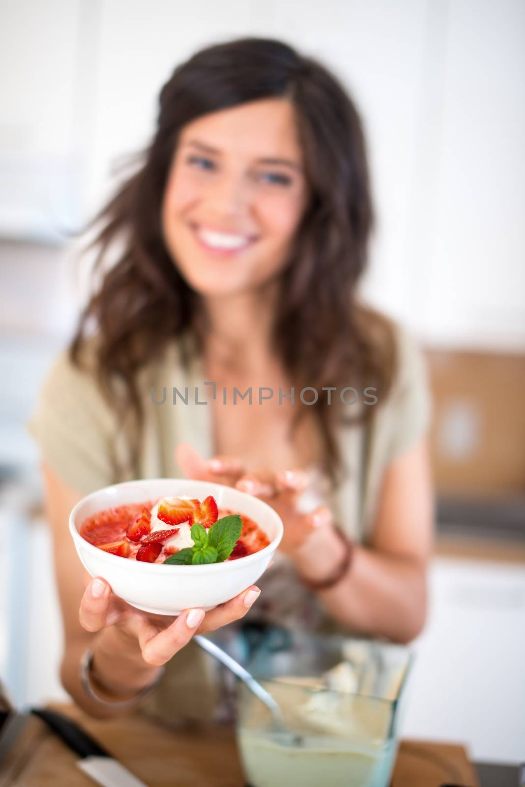 Portrait of a girl using the blender to prepare raw banana ice cream with strawberries