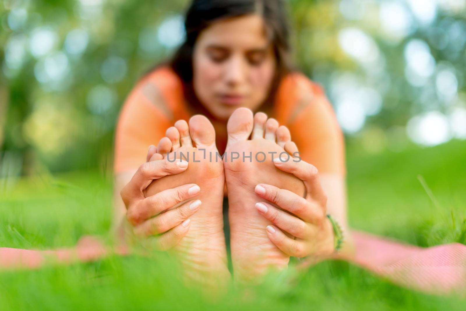 Feet detail of a girl meditation and taking a yoga pose at sunset under trees