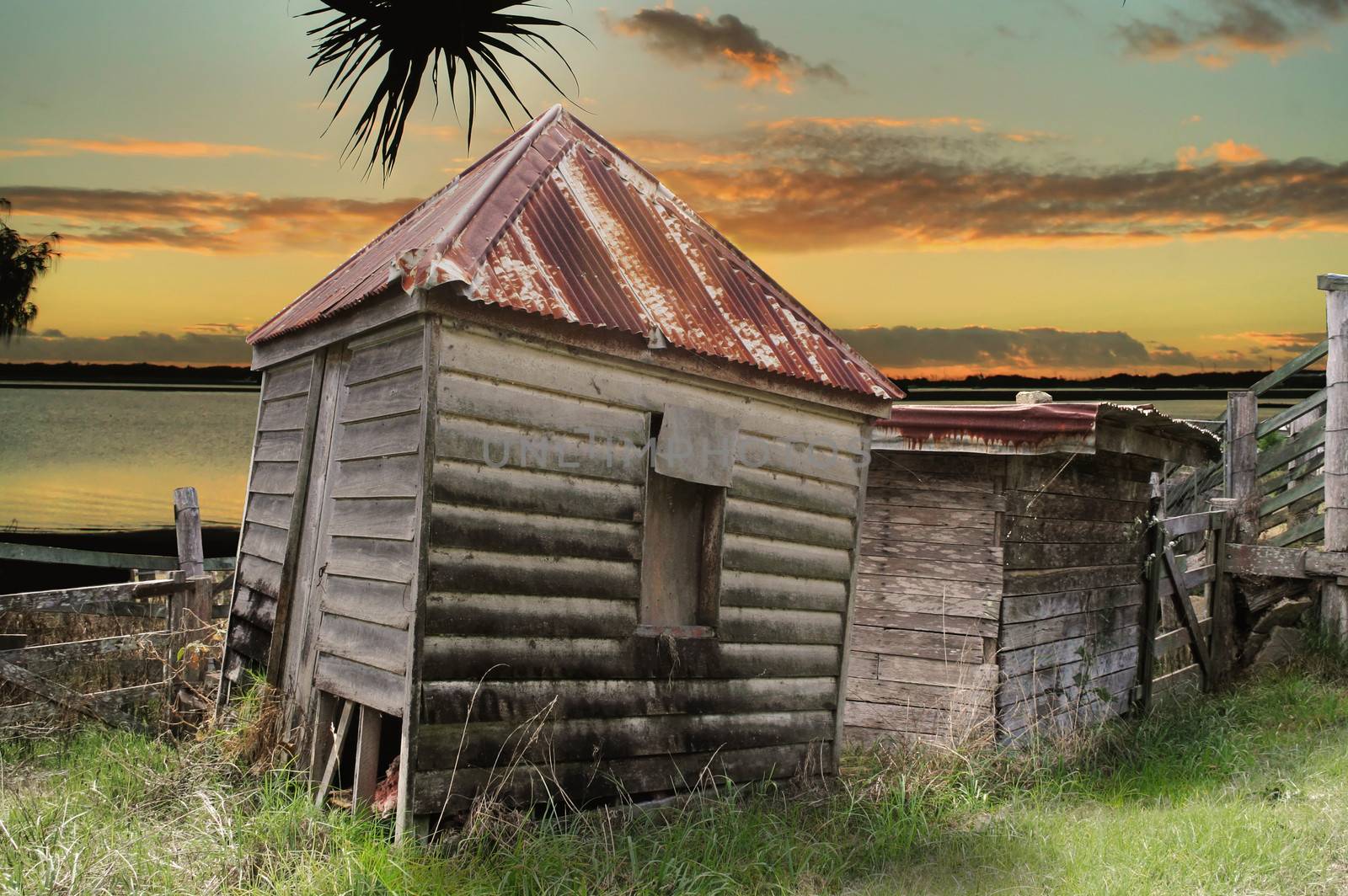 Old rundown and dilapidated huts by the water at sunset.