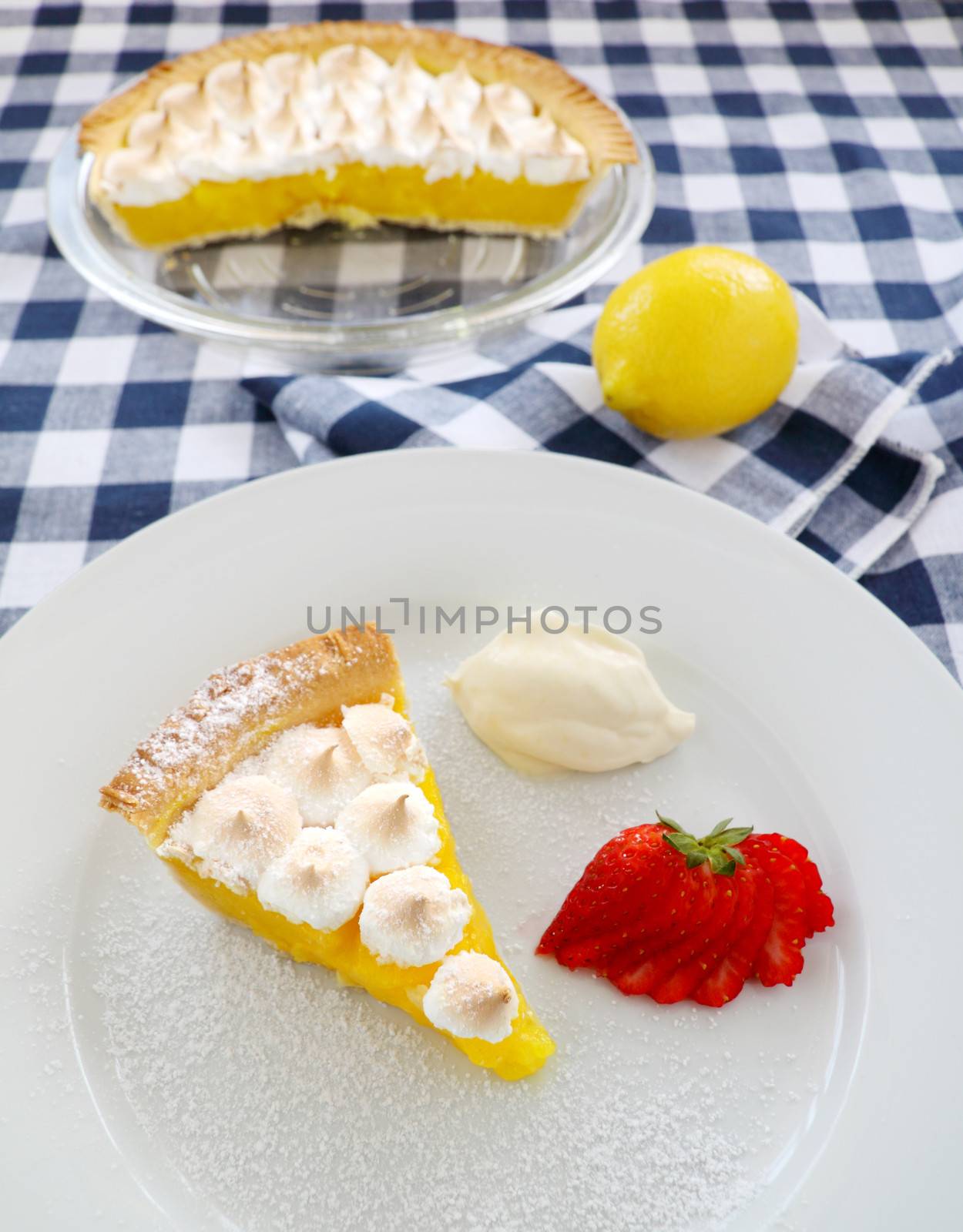 Delightful slice of lemon meringue pie with strawberries and cream.