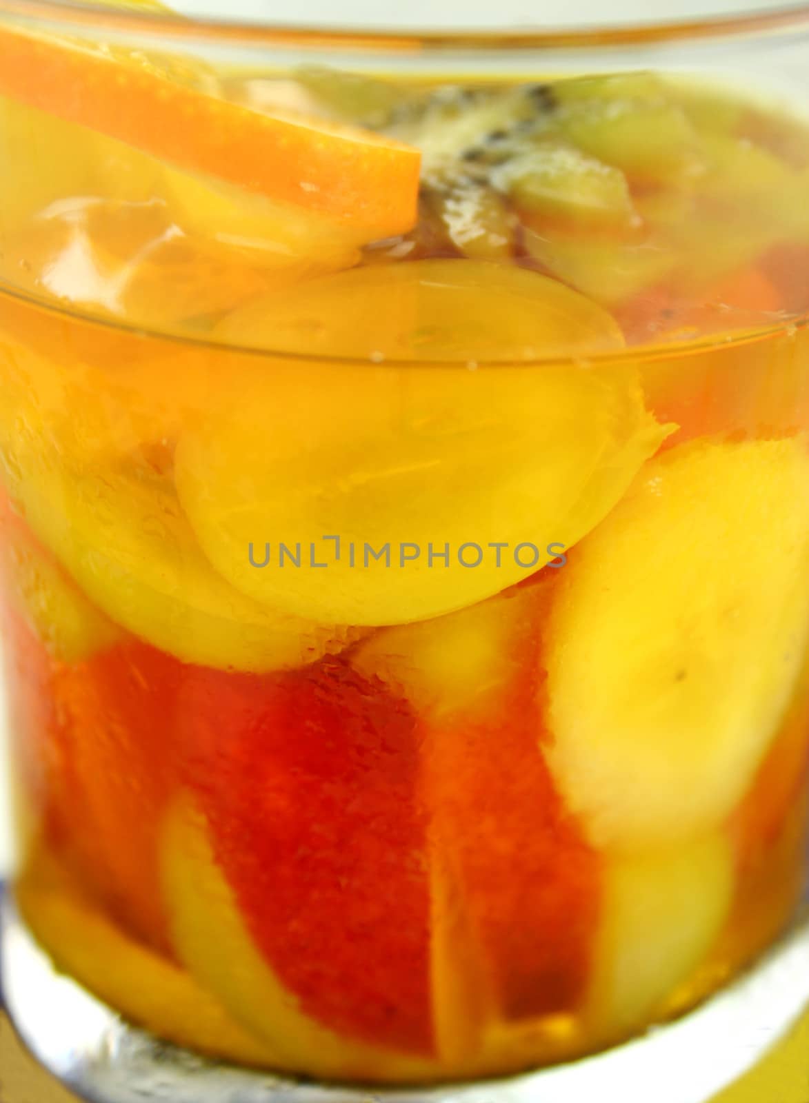 Fresh sliced tropical fruit set in pineapple jelly in a glass.