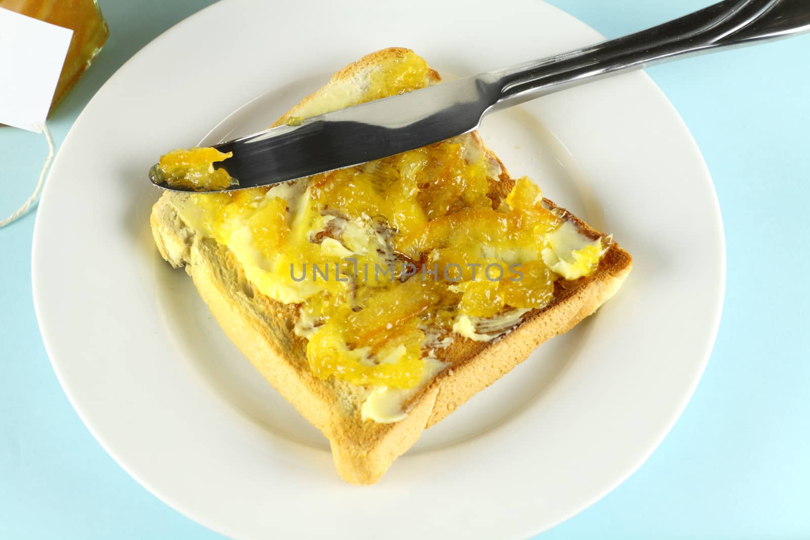 Orange marmalade spread on a slice of toast with butter.