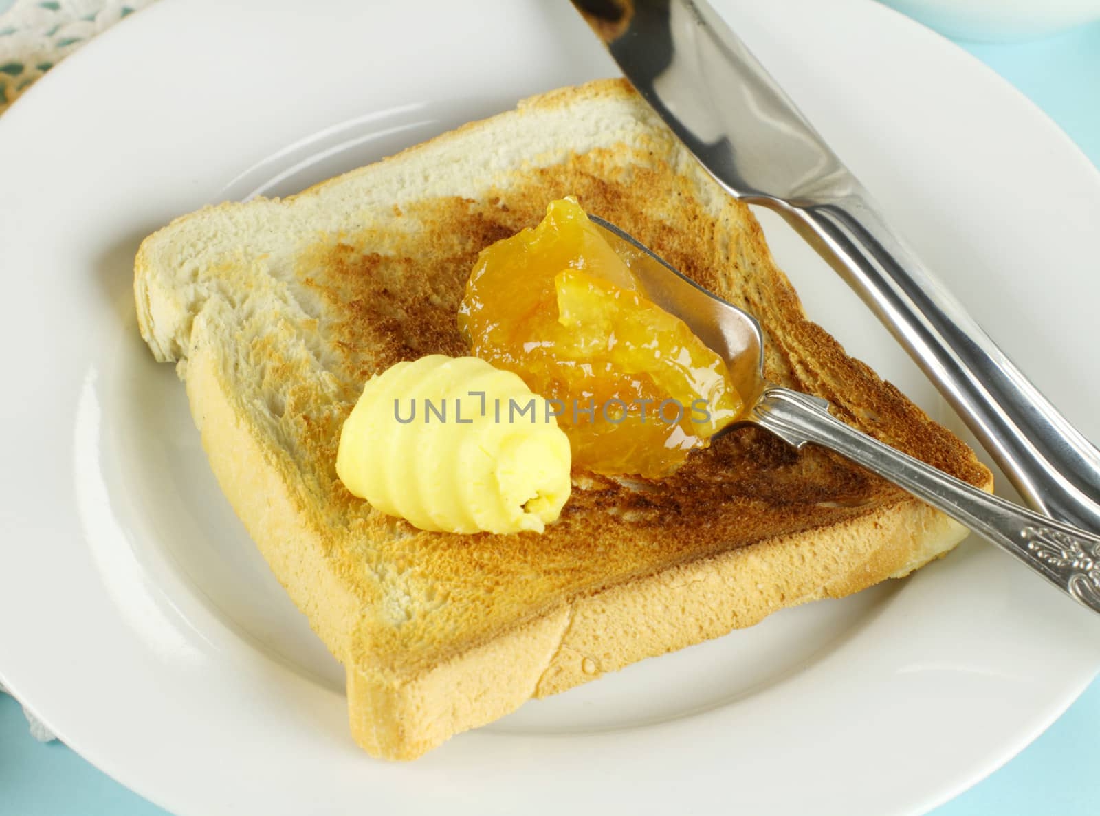 Dollops of orange marmalade and butter on a slice of toast.